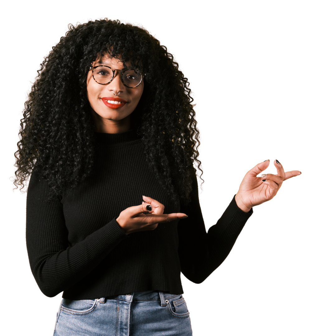 A young woman with curly black hair, glasses, and red lipstick is smiling and gesturing with her hands, wearing a black long-sleeve shirt and blue jeans.