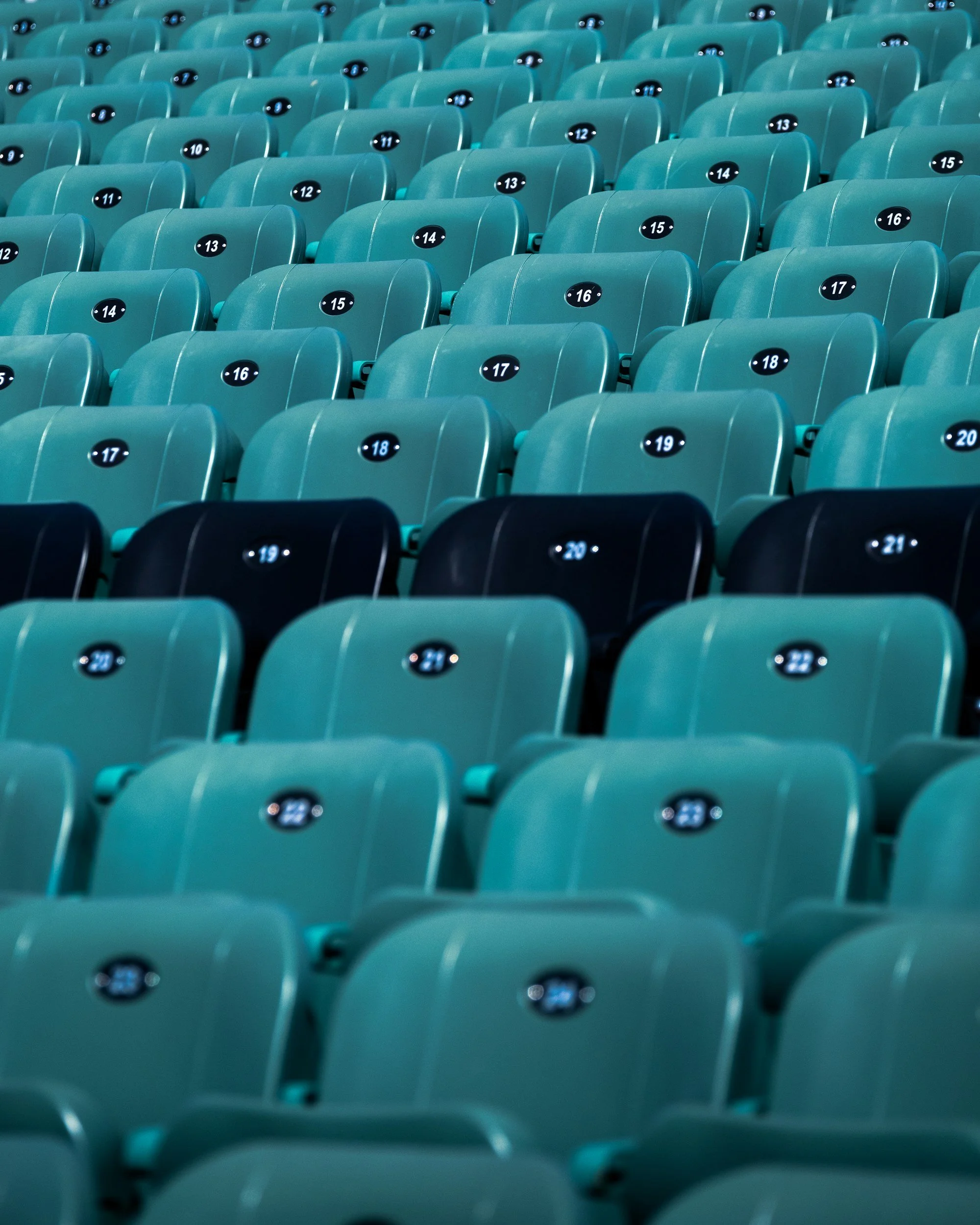 Empty teal stadium seats with numbered black oval labels.
