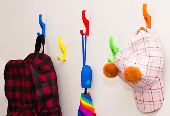 Red, blue, yellow, and orange hooks on the wall, each holding an umbrella, backpack, and hat.