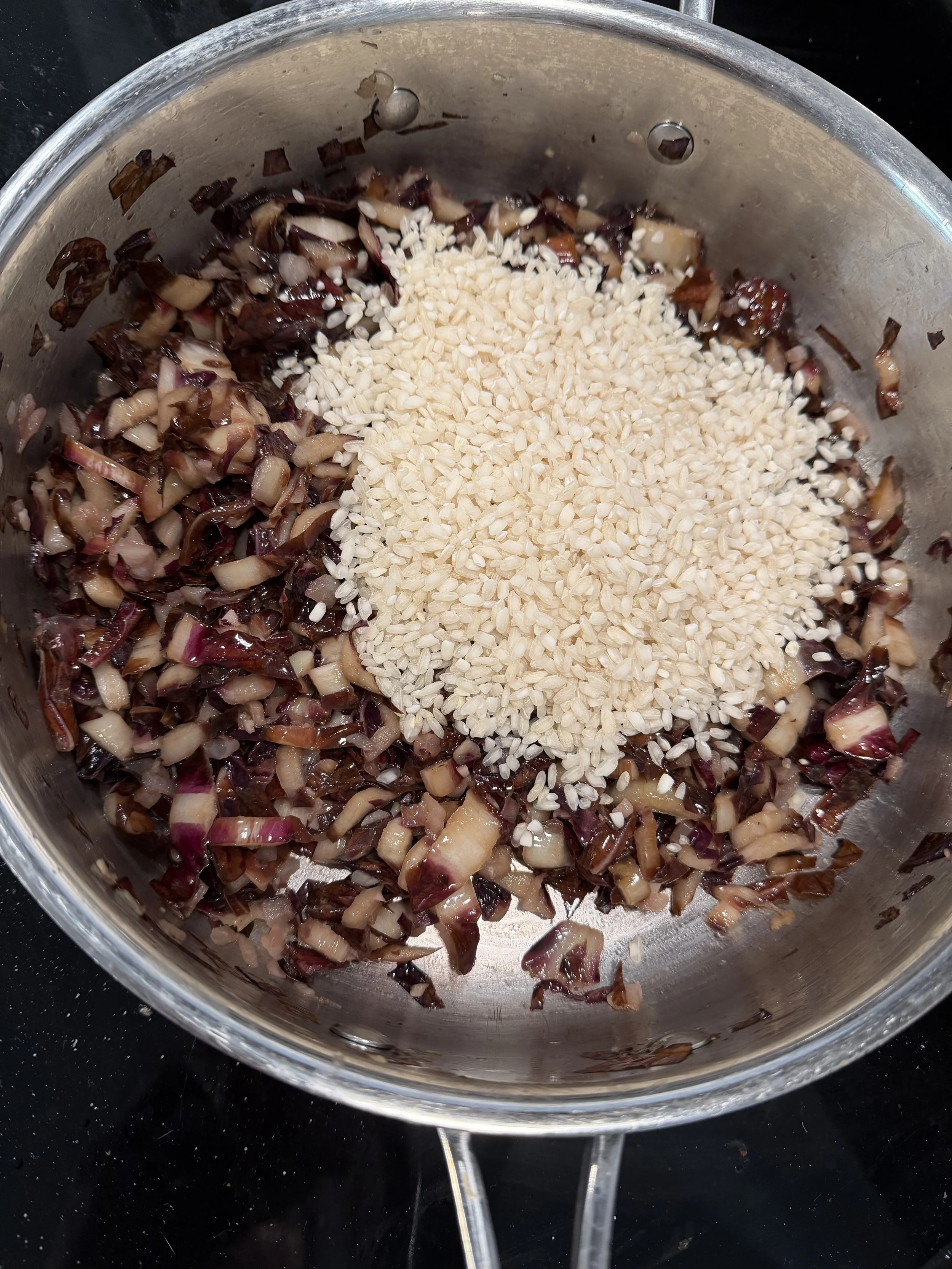 Add rice to toast, mixing together the onion, garlic and radicchio with the rice to meld flavors for the recipe and pairings section of Terragena featuring Wiley Rose of Pinot Noir 