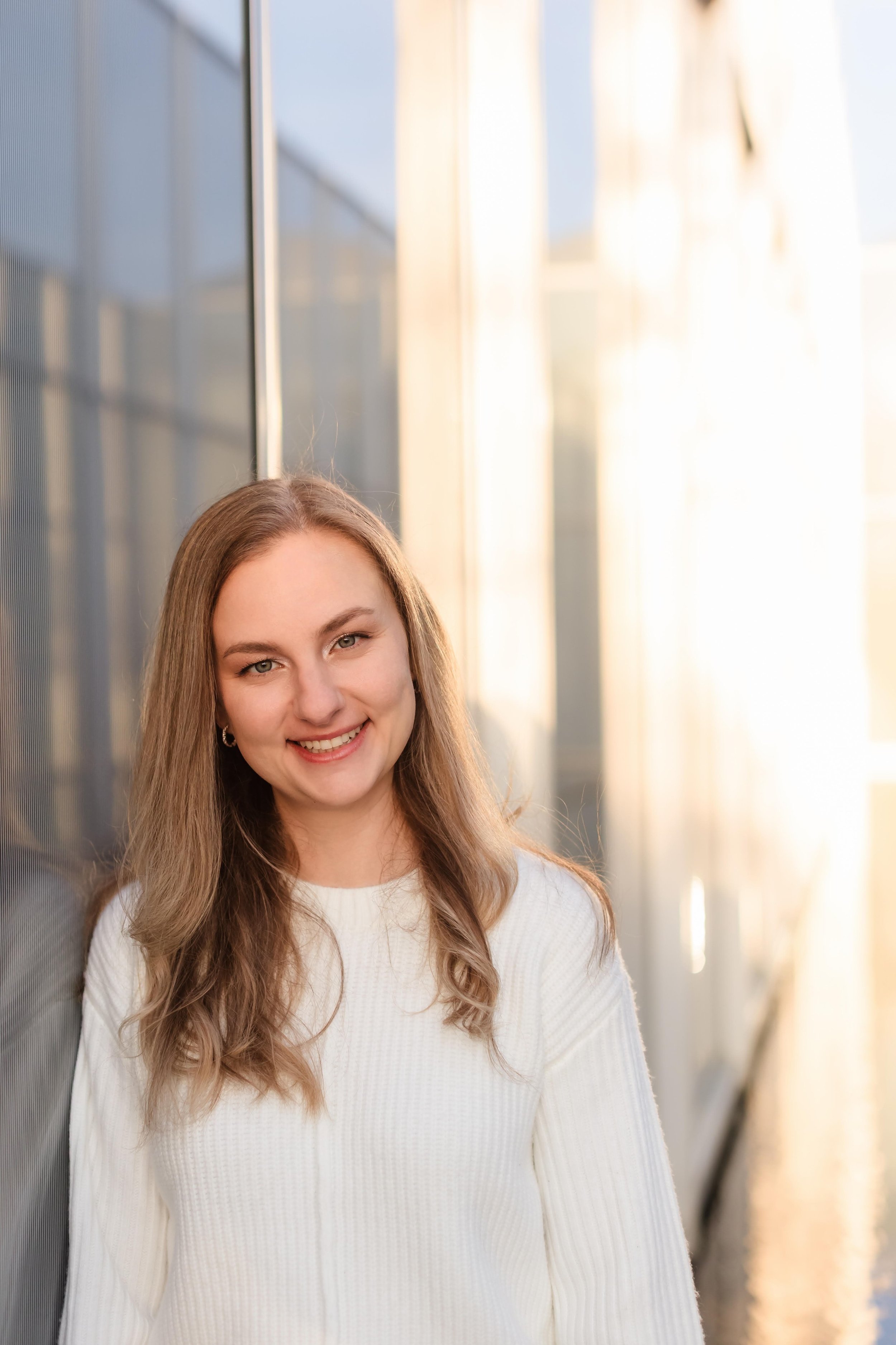 Portrait of Kelsey Parker, a licensed clinical mental health counselor, smiling and standing by a sunlit window in a bright, professional setting.