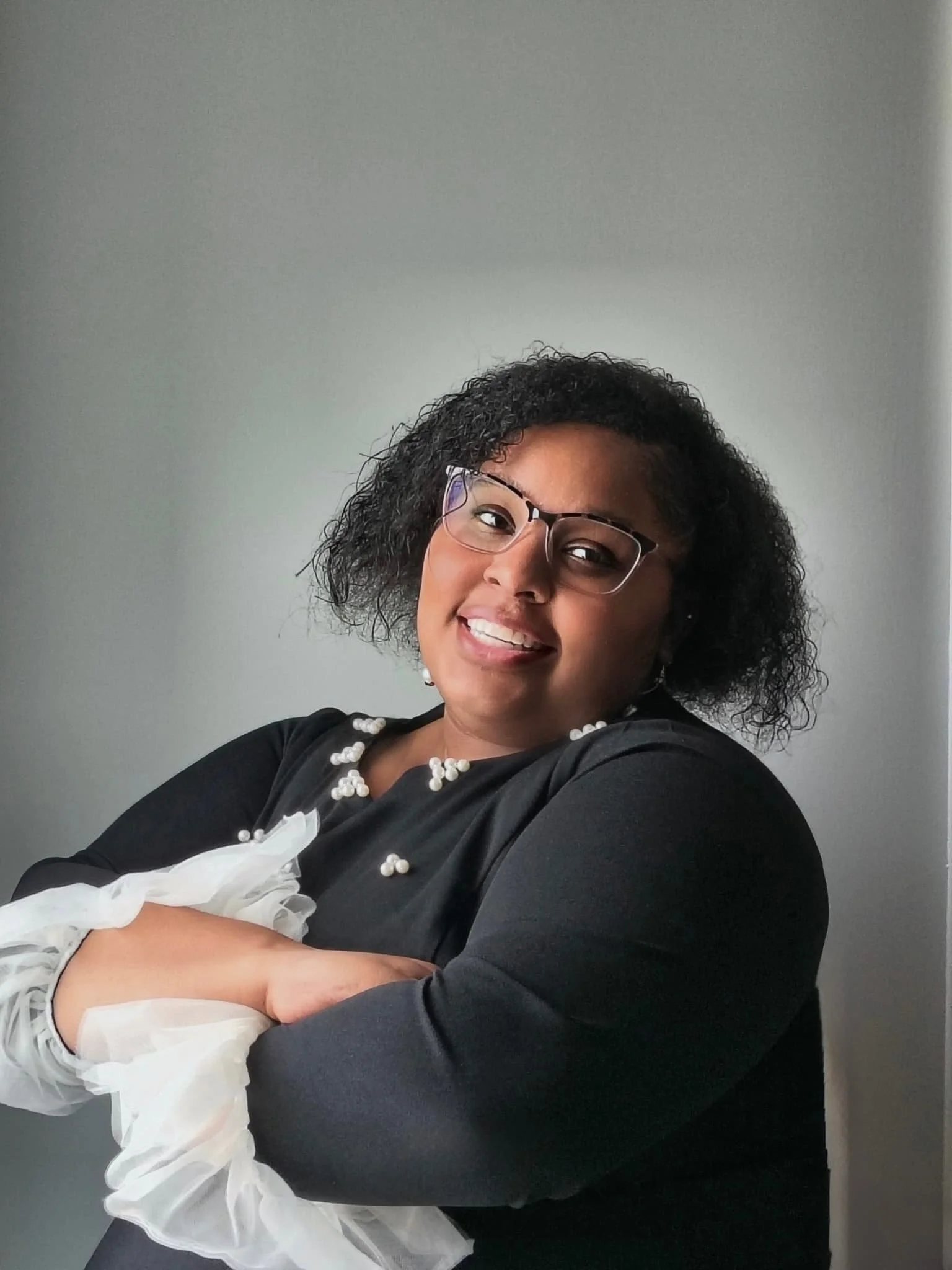 Portrait of Kelsey Parker, a licensed clinical mental health counselor, smiling and standing by a sunlit window in a bright, professional setting.
