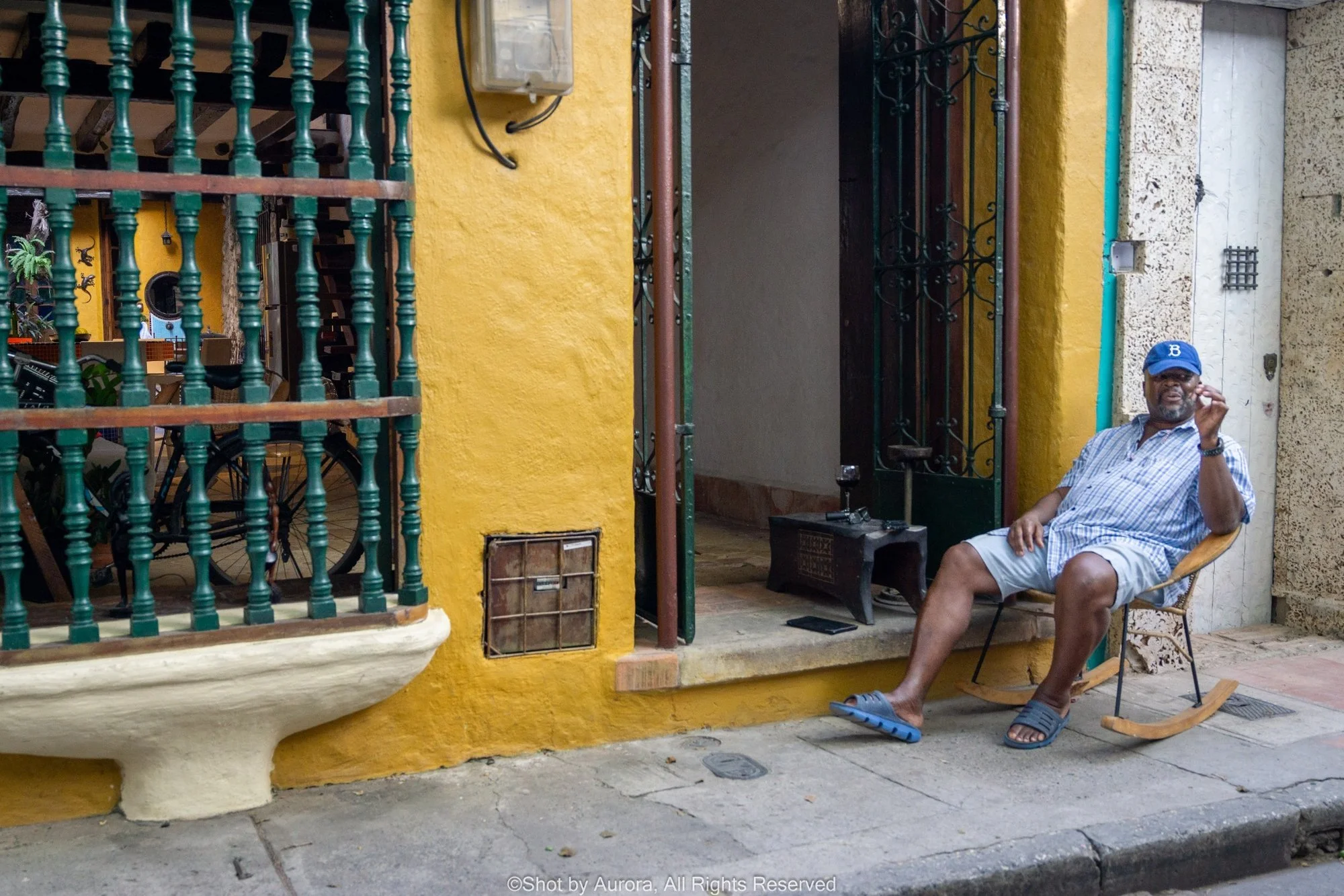 man-smoking-on-porch-yellow-wall-cartagena-colombia-by-aurora.jpg