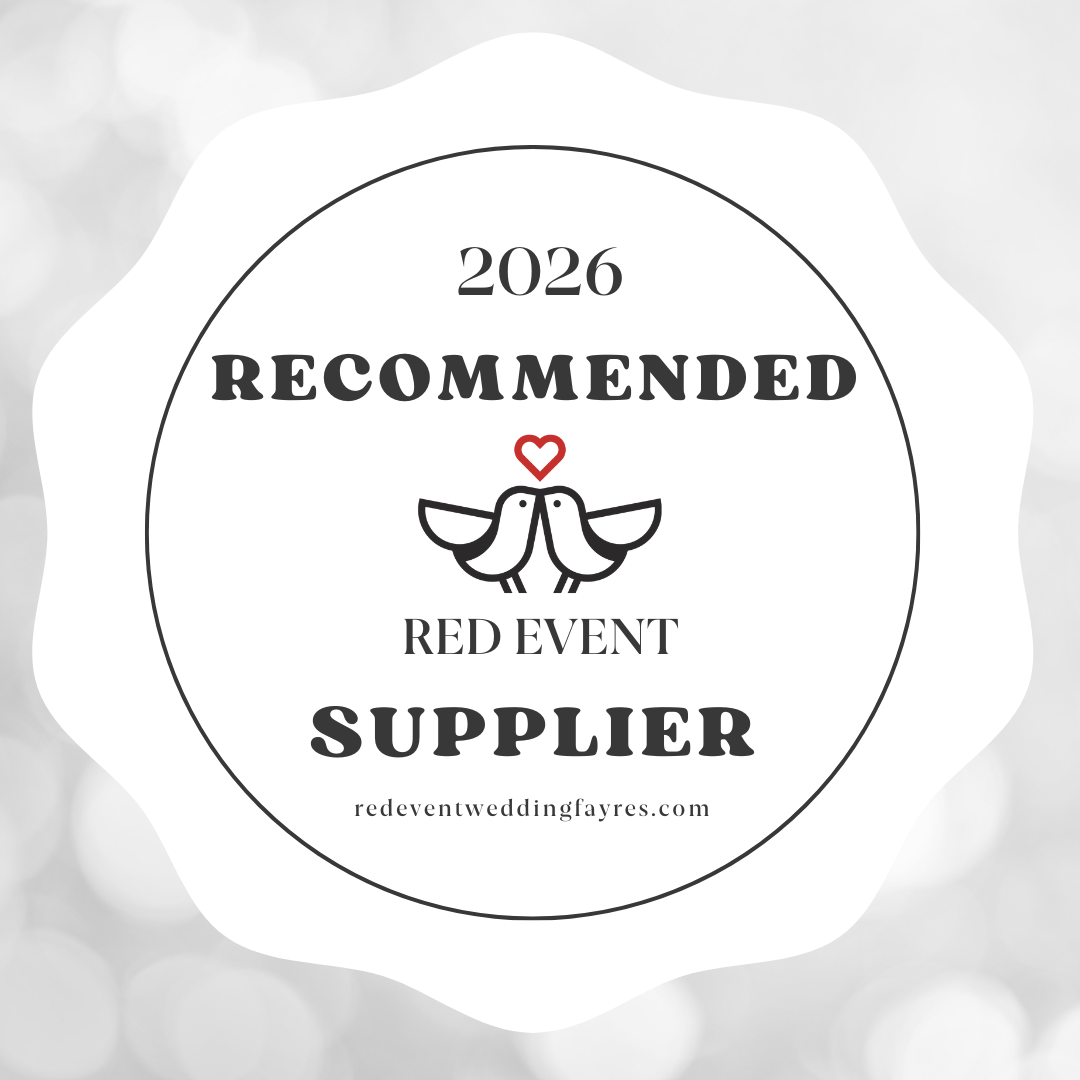 A circular badge with a black border and text indicating a 2026 recommended supplier for a wedding event, featuring two love birds with a red heart above them and the website reeventweddingfayres.com at the bottom.