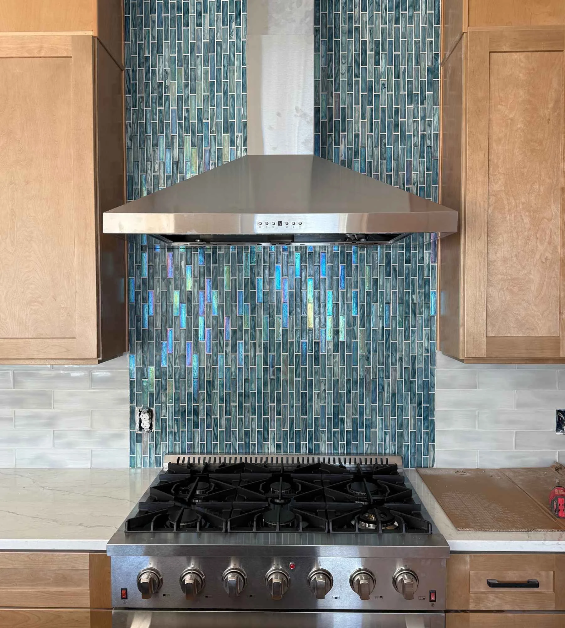 ckd-remodeling-pace-fl-colorful-kitchen-cabinets-and-backsplash-natural-wood-cabinets-vertical-blue-and-green-glass-tile-behind-range-hood-precise.jpg