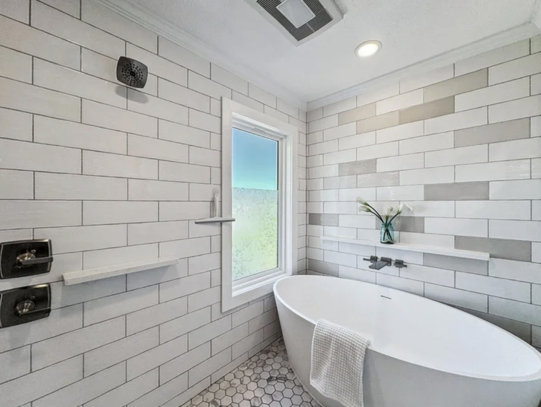ckd-remodeling-pace-fl-bathroom-renovation-tips-soaking-tub-in-shower-window-overlooking-ocean-white-and-gray-colors-quality-bathroom-design.png