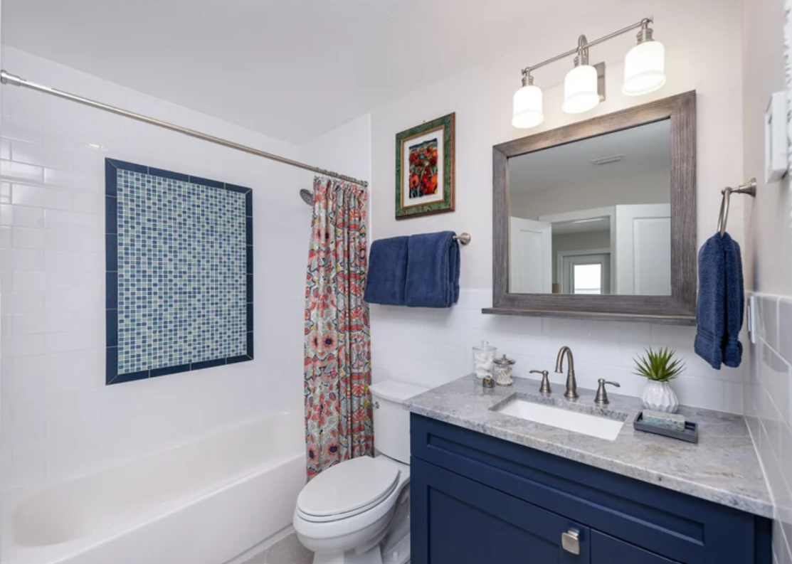 ckd-remodeling-milton-fl-bathroom-renovation-tips-remodeled-bathroom-with-shower-wall-tile-feature-blue-vanity-coastal-personal-design-build.png