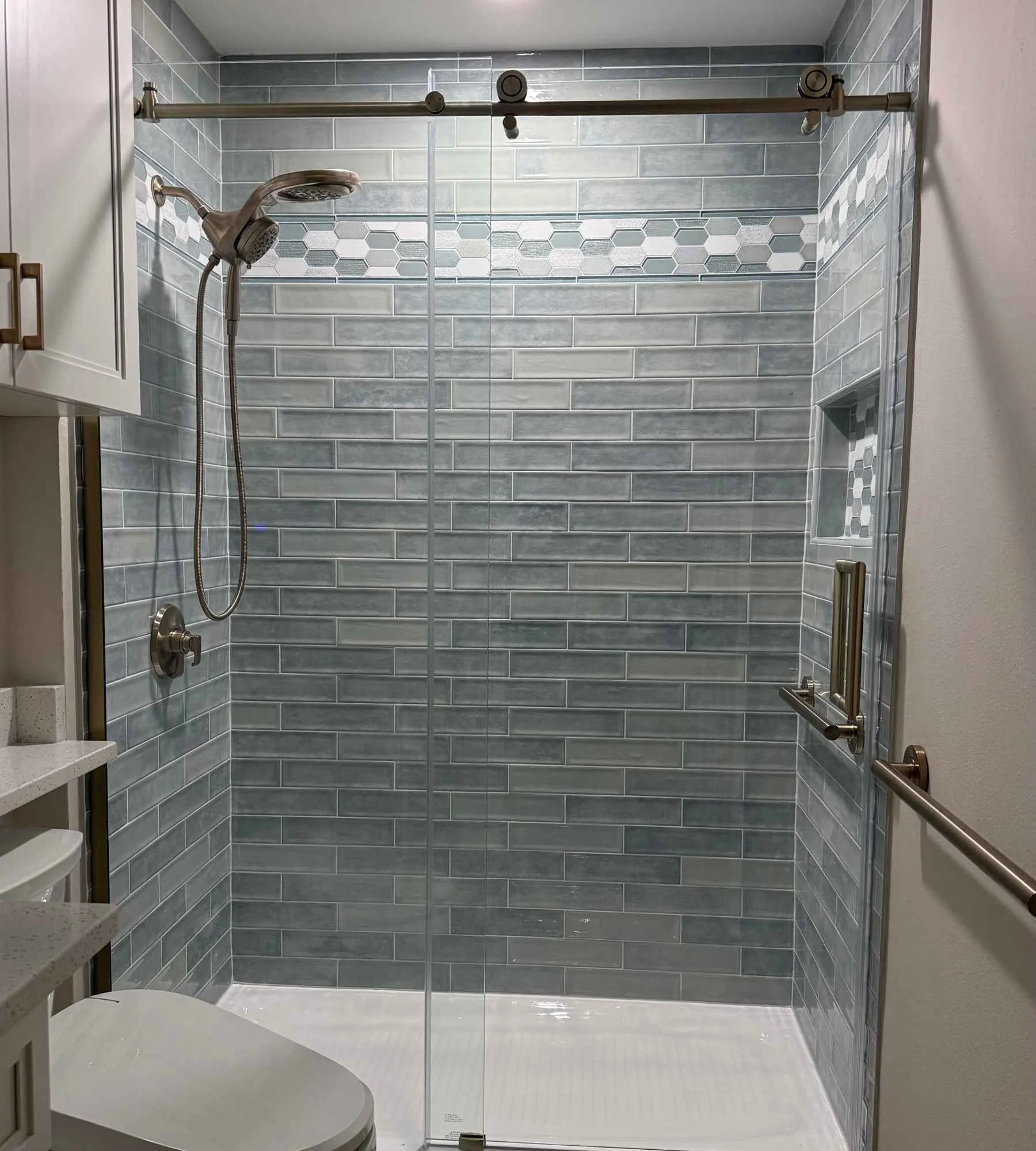 ckd-remodeling-perdido-key-fl-bathroom-design-for-aging-in-place-glass-shower-blue-tile-handheld-shower-head-intentional.jpg