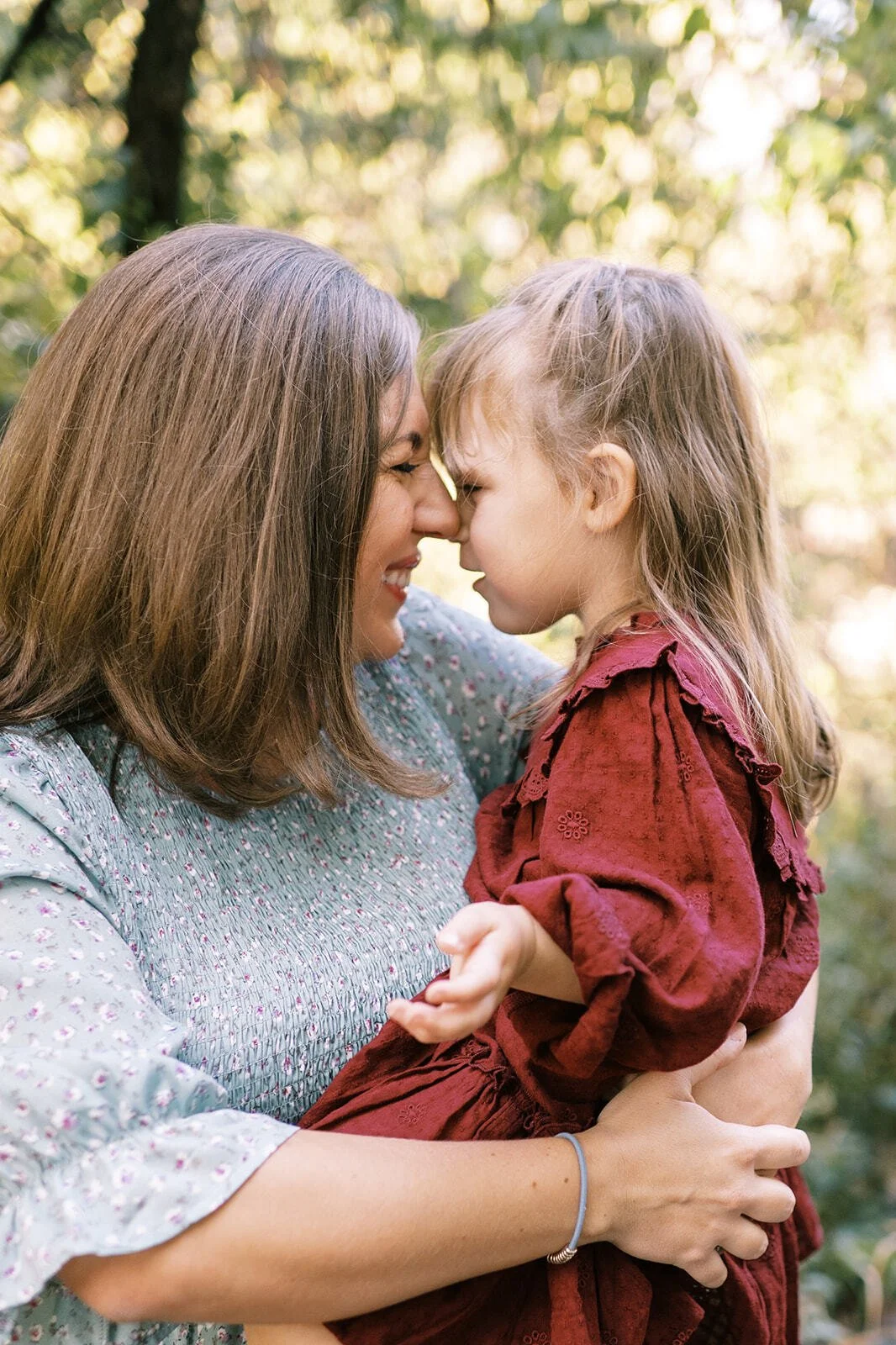 Mother holding her daughter nose-to-nose during an intimate outdoor mother-daughter photoshoot