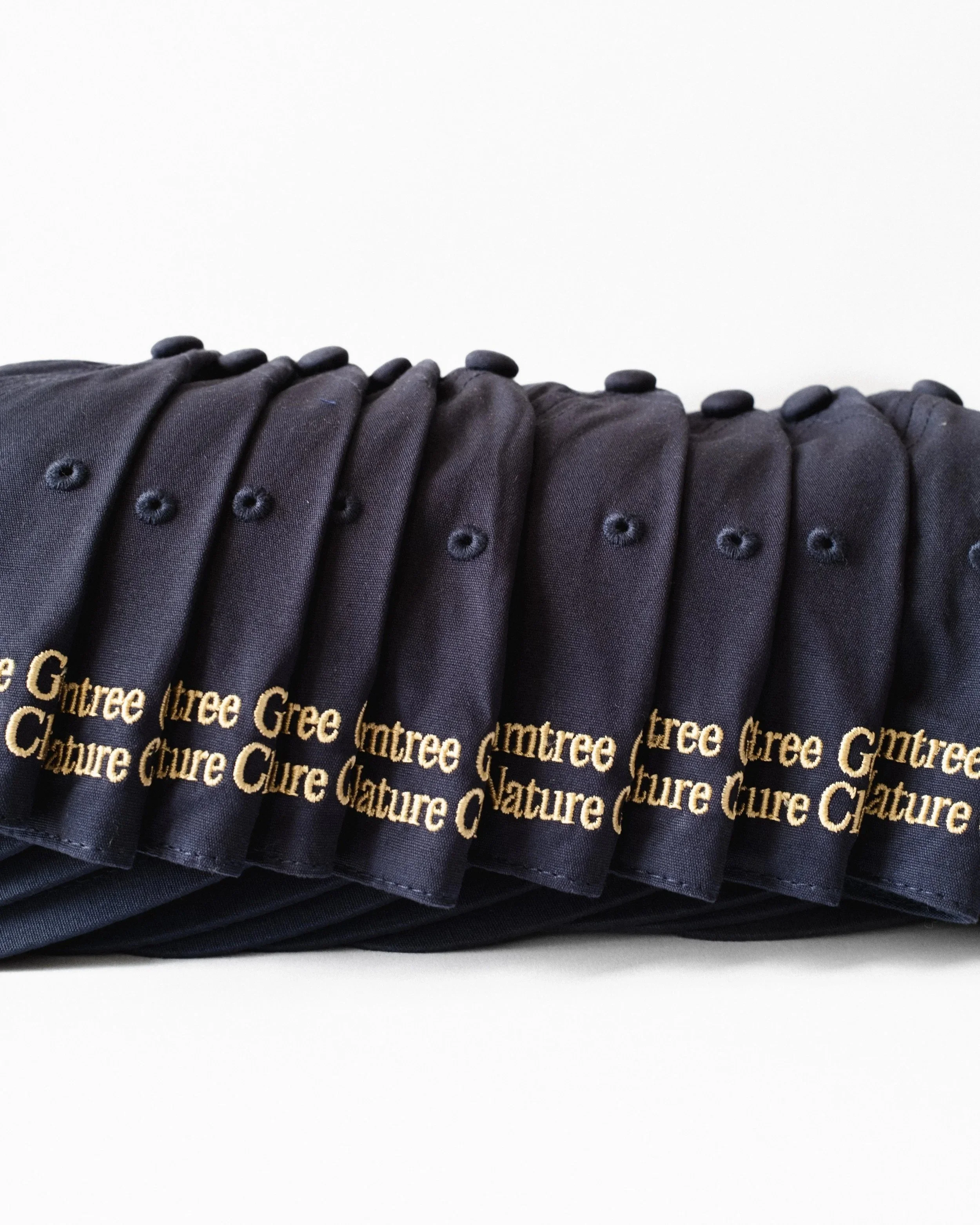 Stack of navy and gold Just Out For A Walk dad hats with gold embroidery