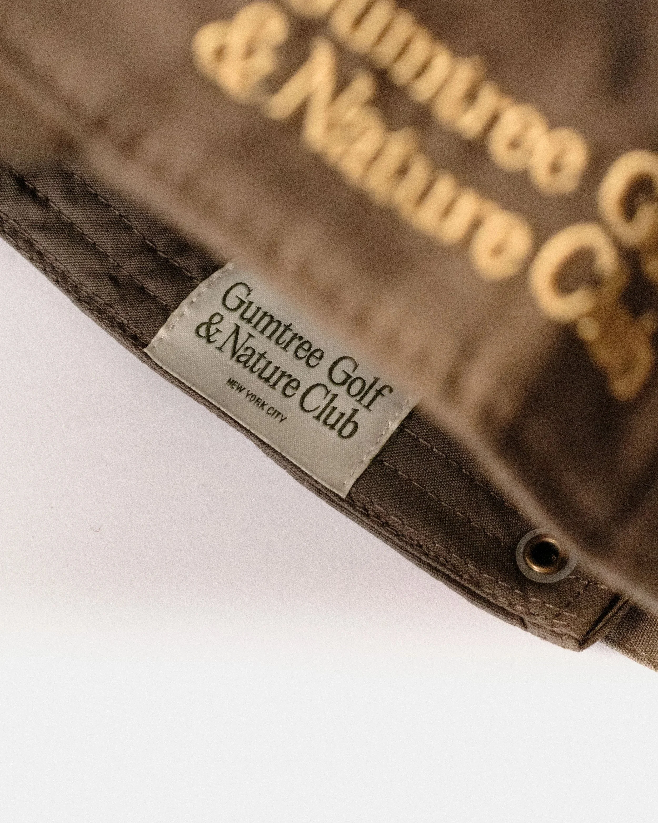 Close-up of the Gumtree Golf & Nature Club woven label on the brown and yellow dad hat