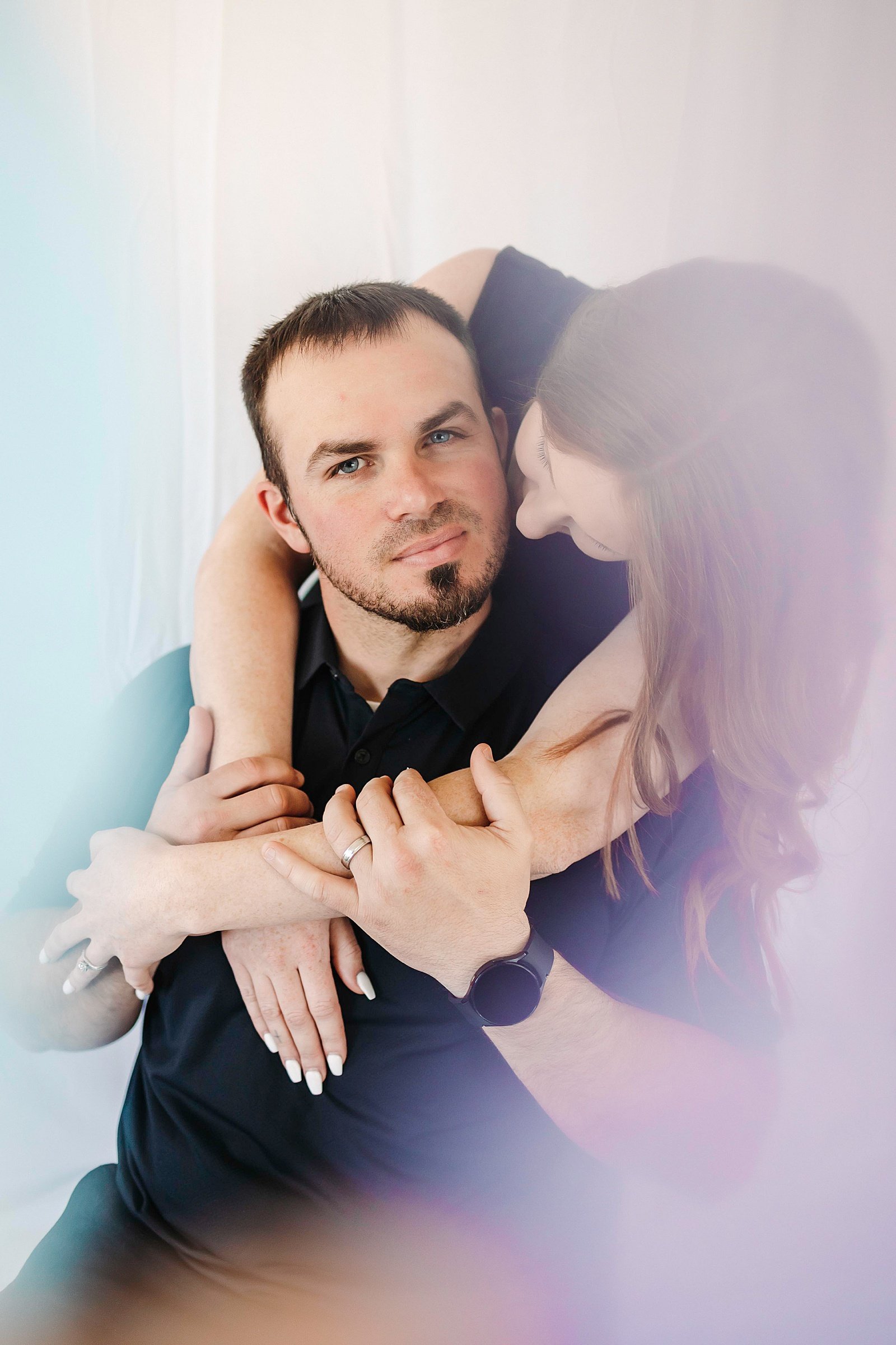  Woman wrapping up man in embrace with colors all around them  