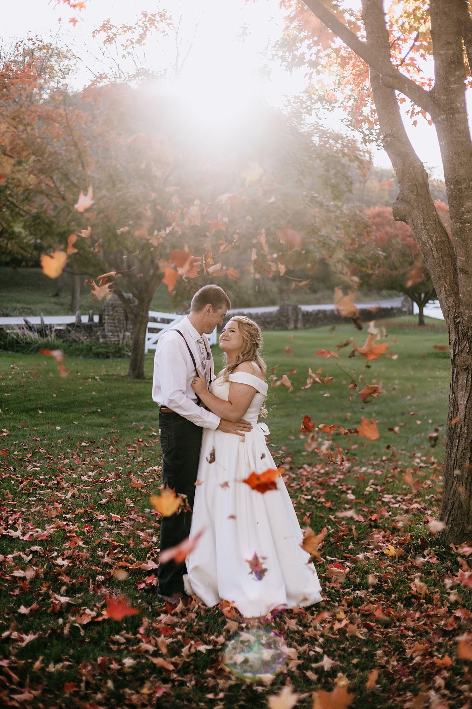  Bride and groom embracing in the golden hour with Fall leaves all around them 