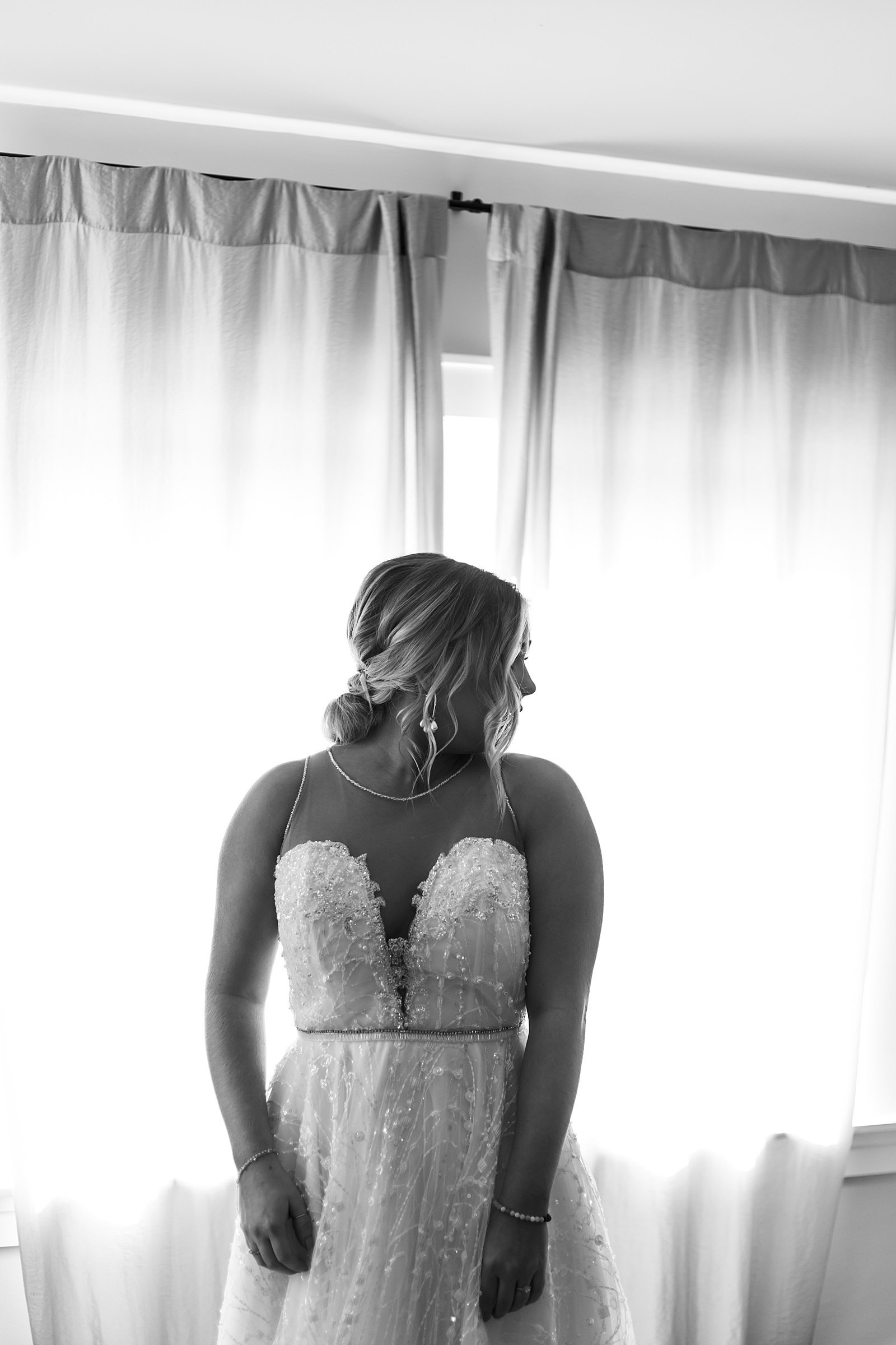  Bride looking over her shoulder in front of a window by Minnesota wedding photographer, McKenzie Berquam. 