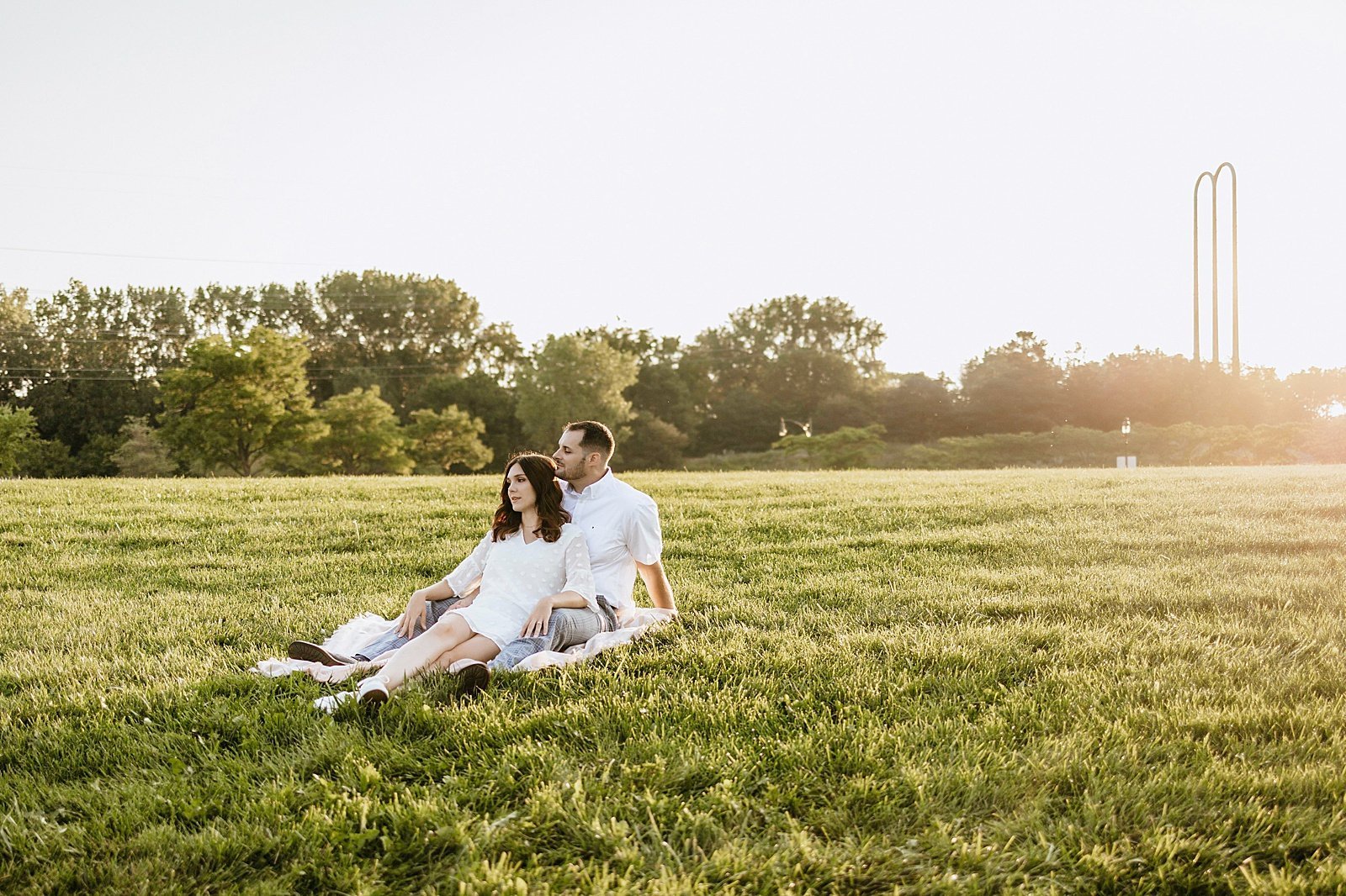  Couple sitting on a picnic blanket in a field at Boom Island Park for their engagement session.  