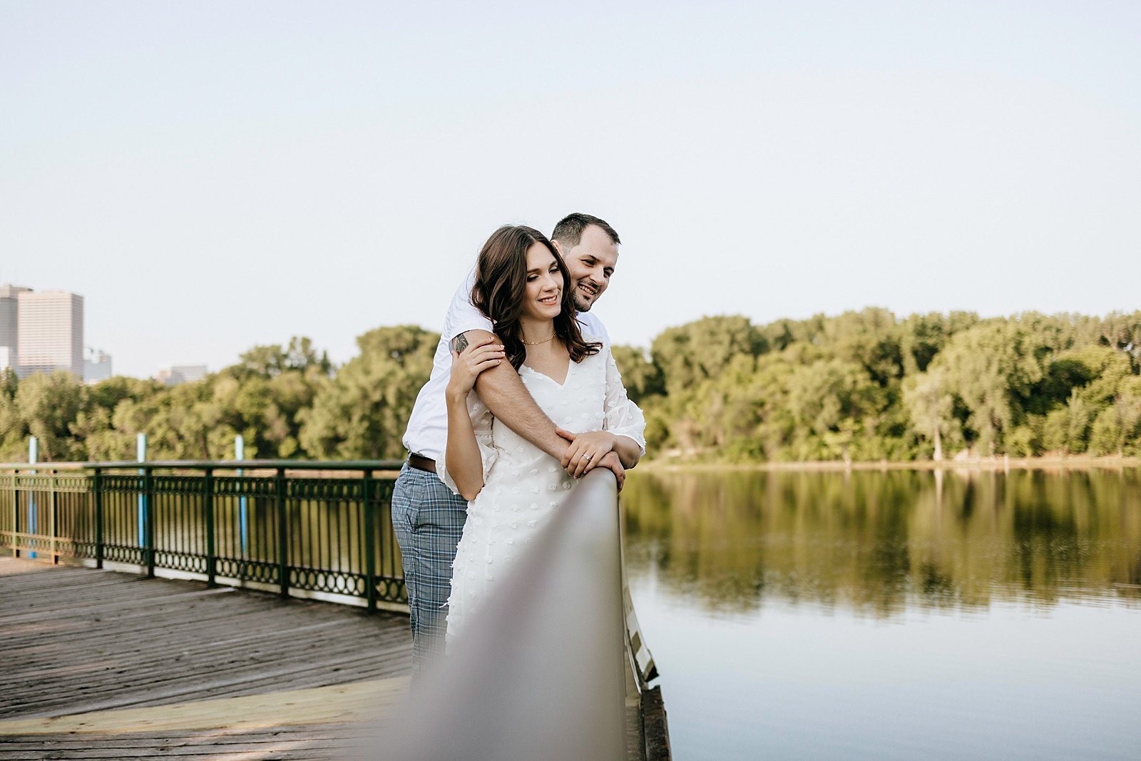  Couple hugging on a dock over pond at Boom Island Park for their engagement session.  