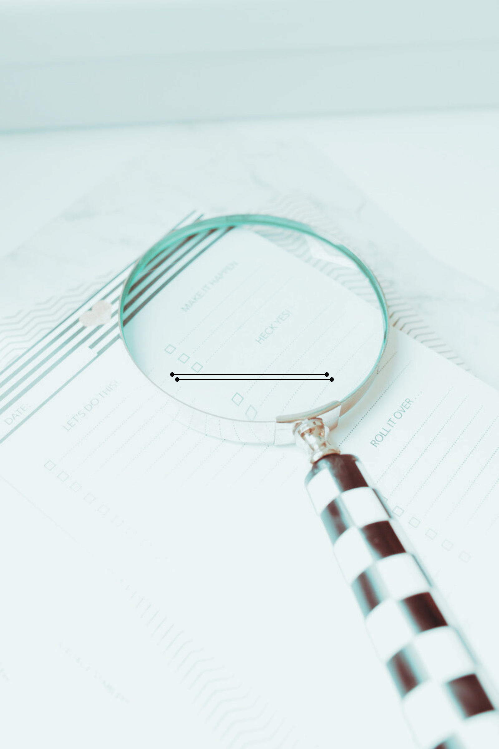 A checklist and a pen under a magnifying glass on a sheet of paper.