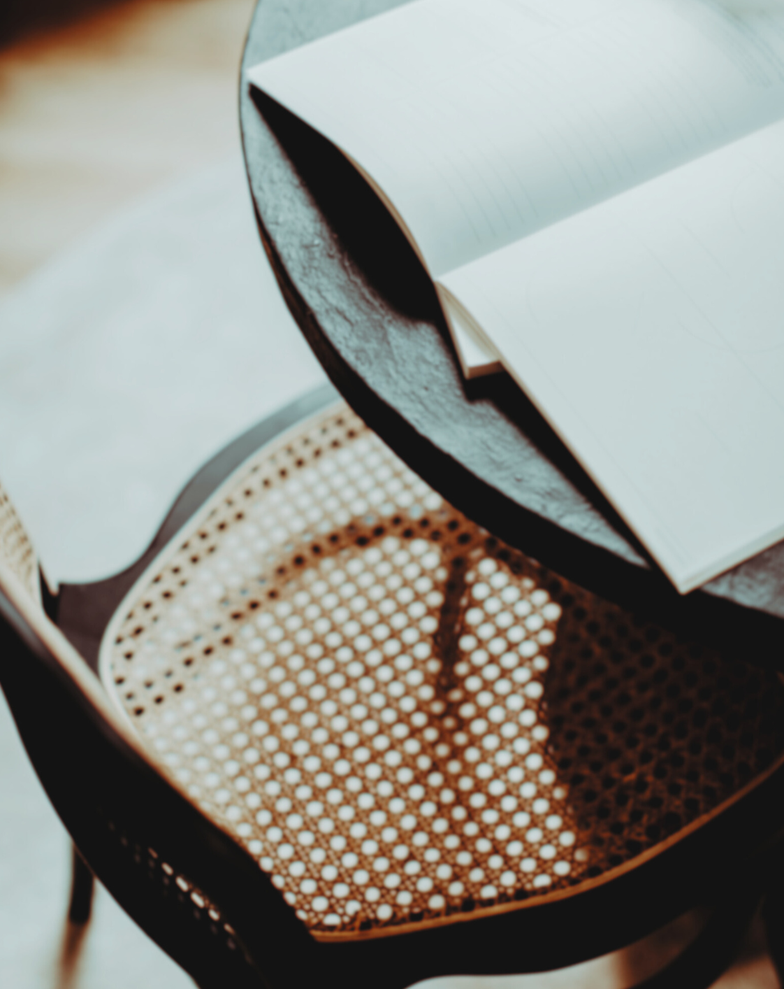 Open notebook resting on a black chair with a rattan seat.