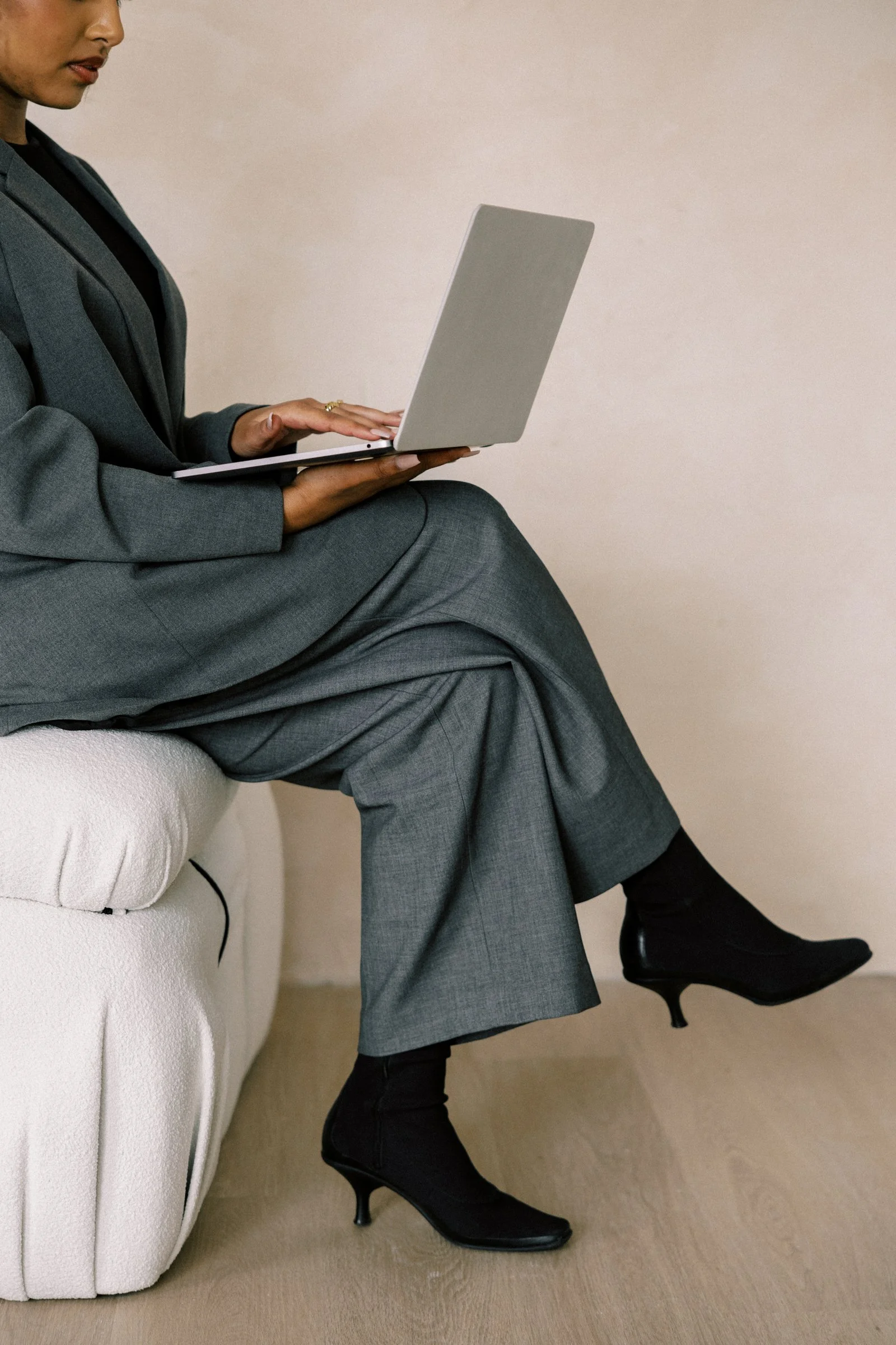 Woman in grey suit on a laptop - Human Design coach for women in midlife