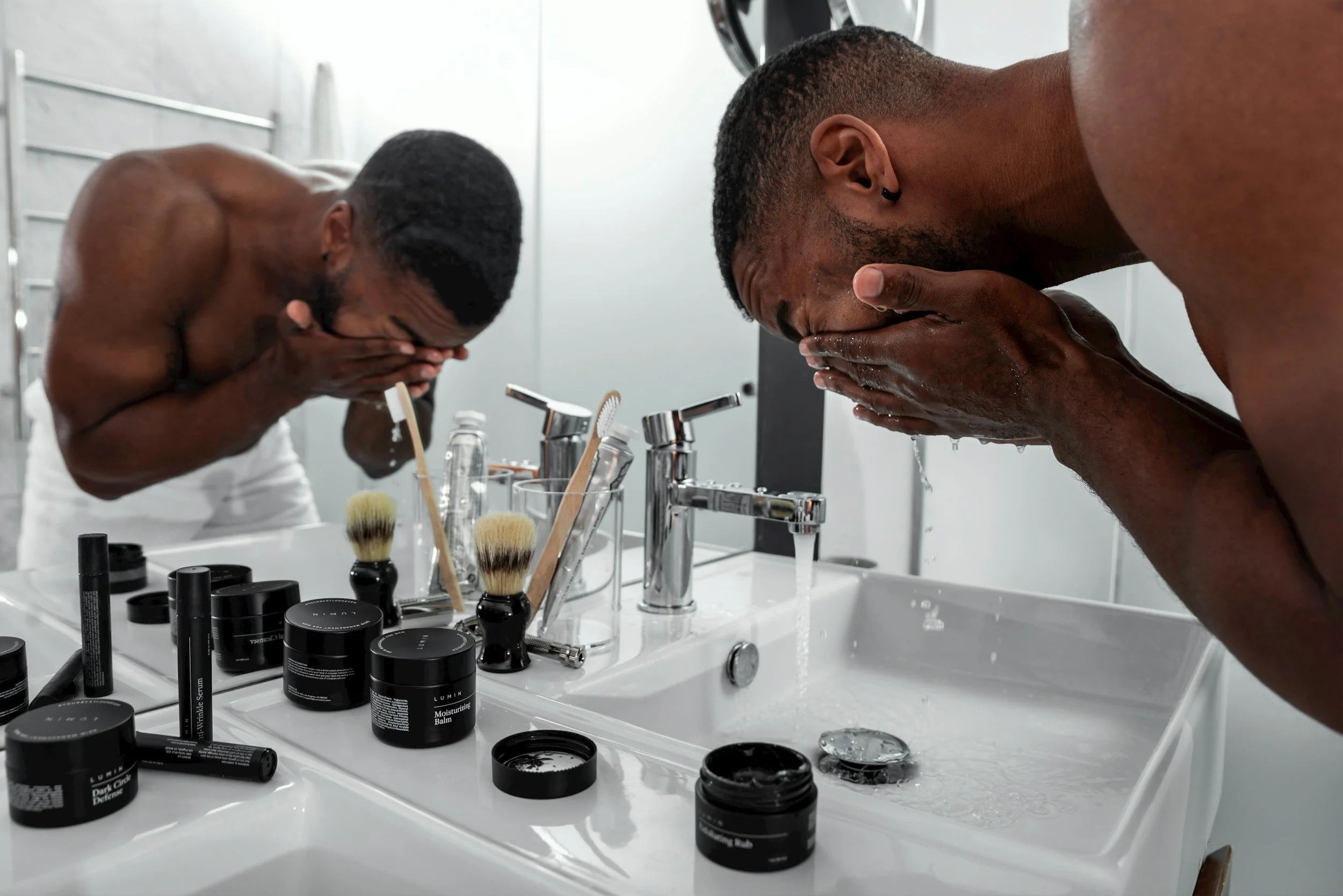 Black man washing his face as part of a professional grooming and skincare routine.
