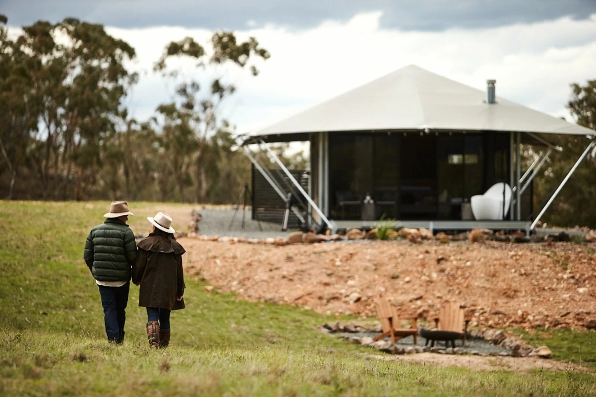 Couple walking near a glamping tent at Wildnest Farmstay in Capertee Valley NSW for an adults only spring glamping escape