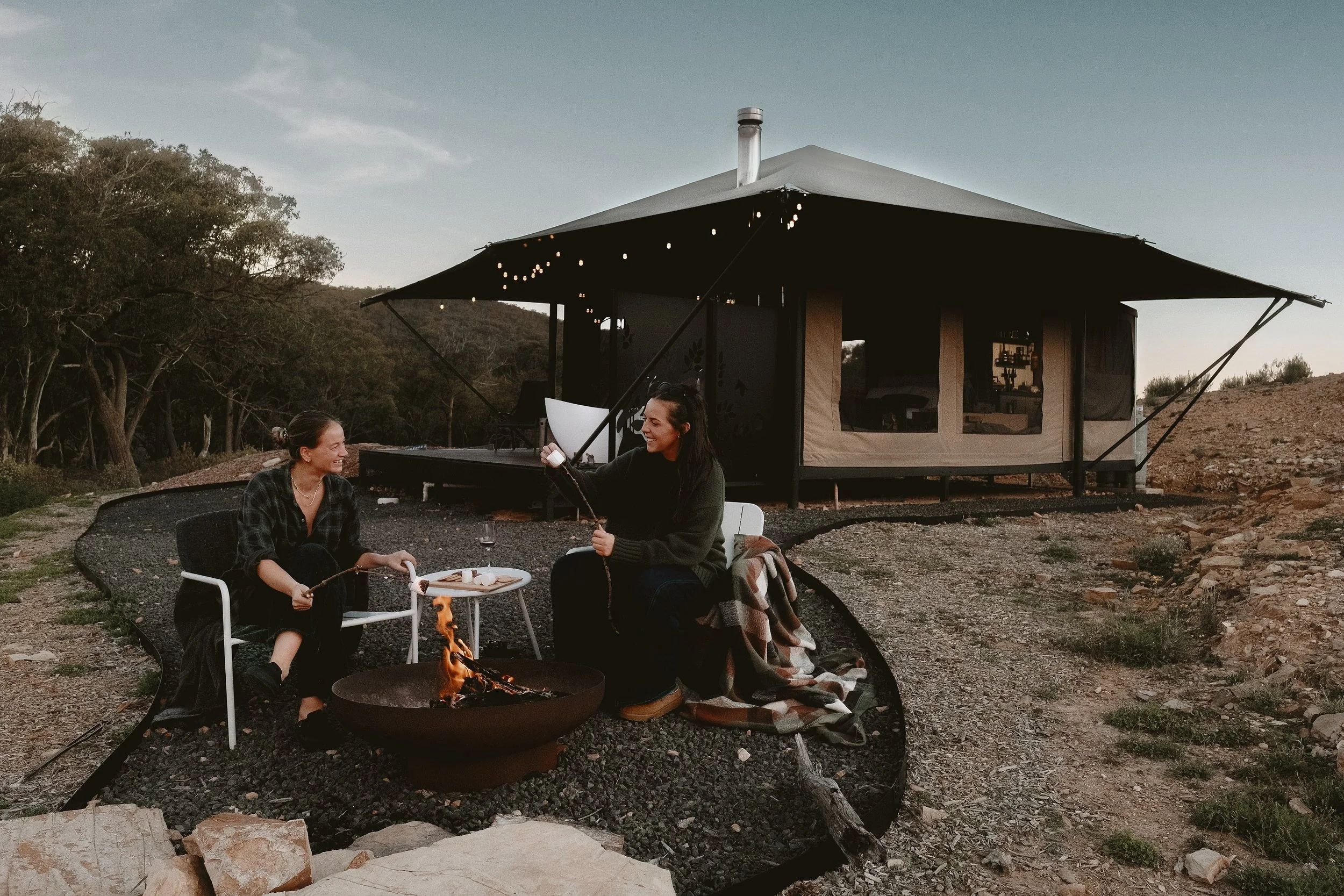 Guests enjoying s’mores by an outdoor fire pit beside their glamping tent at Wildnest Wilderness near Bathurst, NSW, photography by Helen Cooper