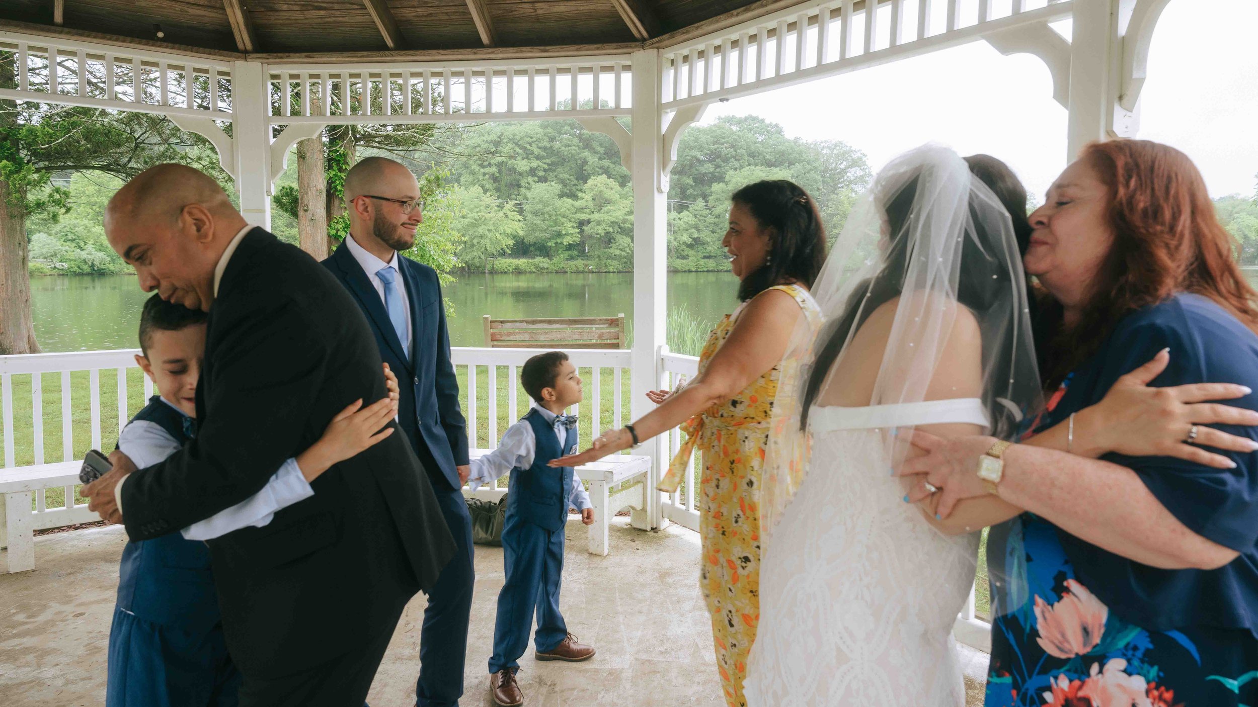 grandpa hugging teary eyed grandson, mother of groom embracing groom for a hug and bride hugging family member