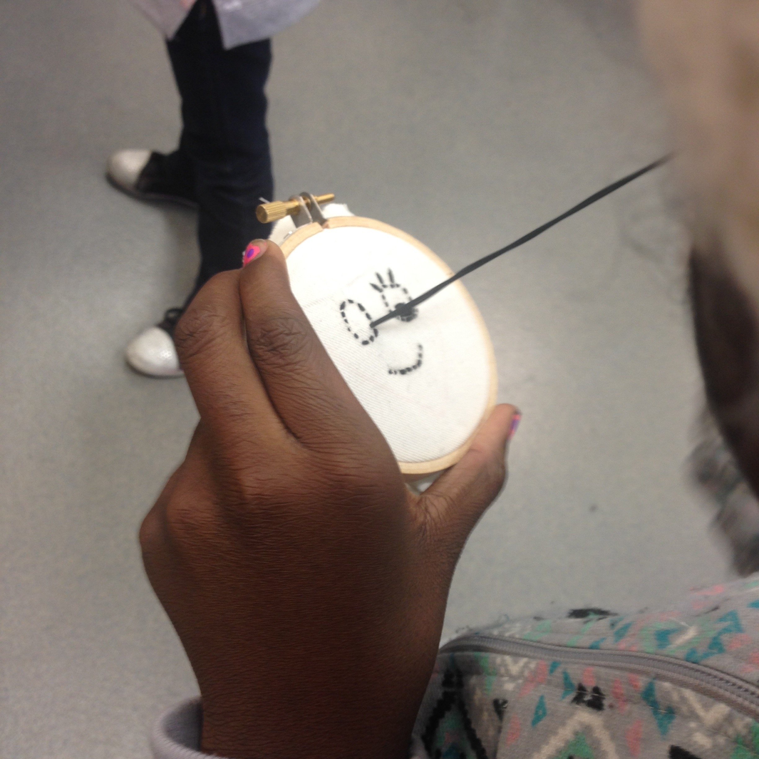 Student embroidering a smiley patch in sewing club.