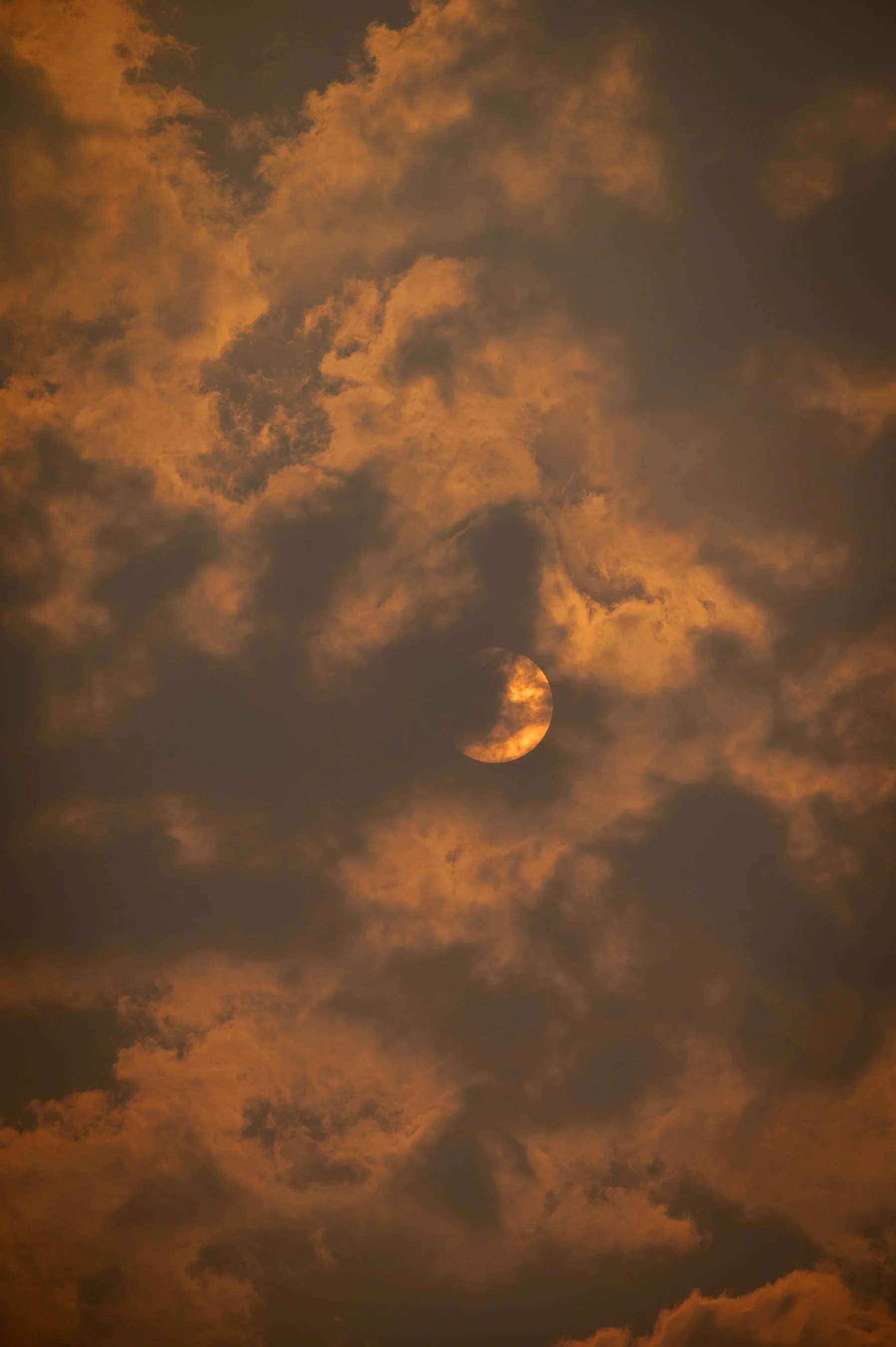 Sun obscured by clouds with a warm orange glow