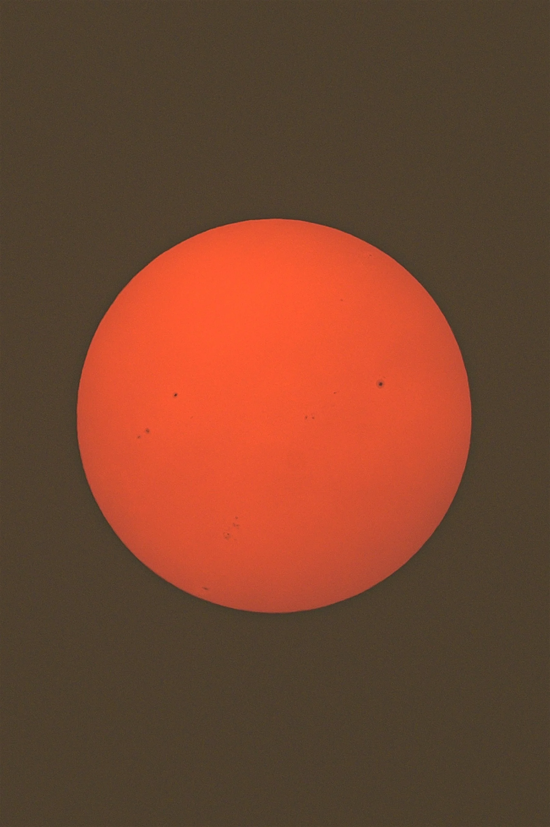 Close-up of the sun with visible sunspots, against a dark background.