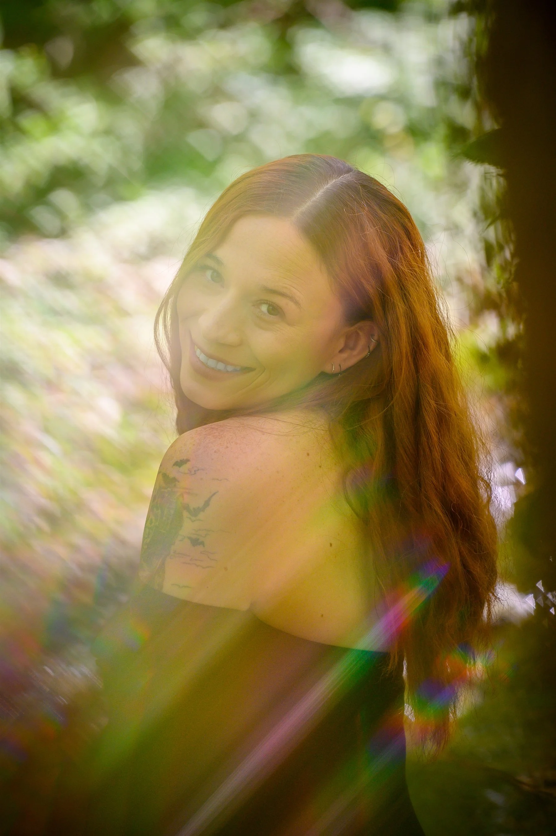 Woman with long hair smiling at the camera, surrounded by a dreamy, nature background and colorful light effects.
