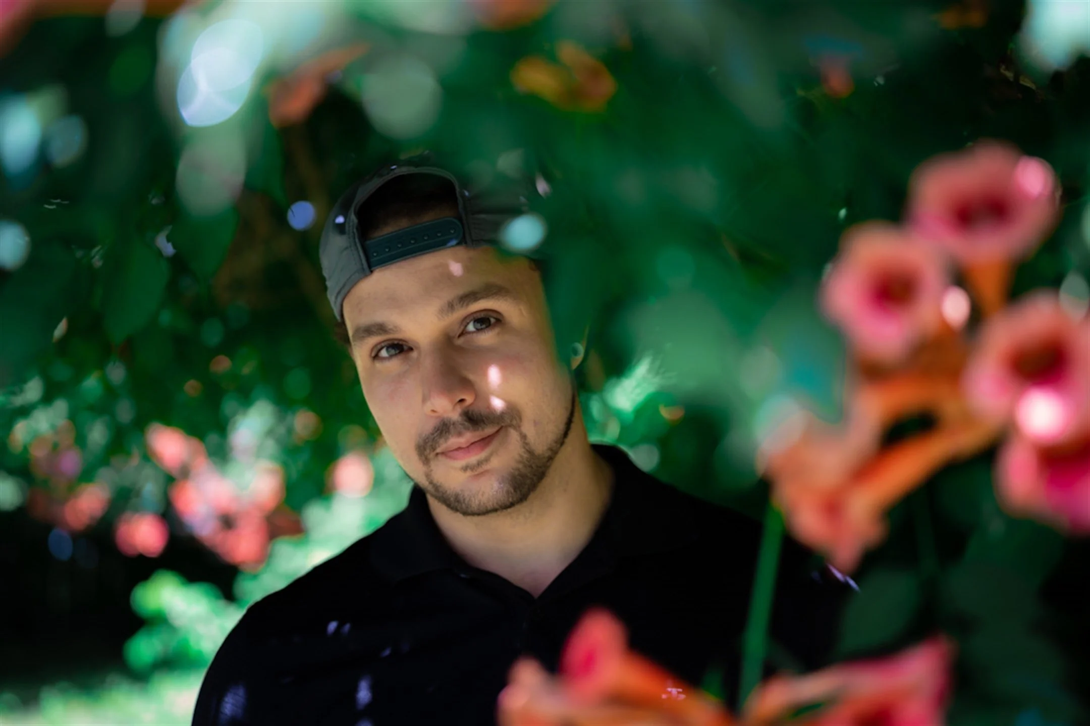 Man wearing a cap in a garden with colorful flowers
