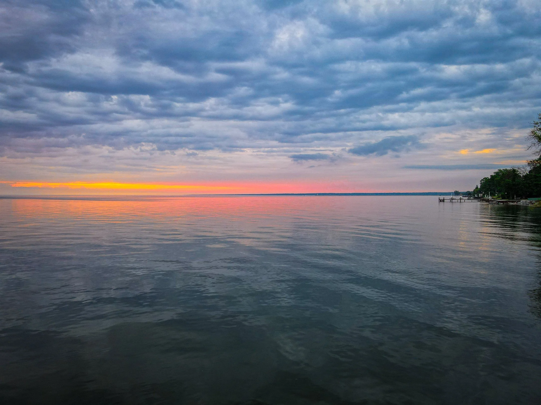 Serene lake at sunrise with colorful sky and clouds.