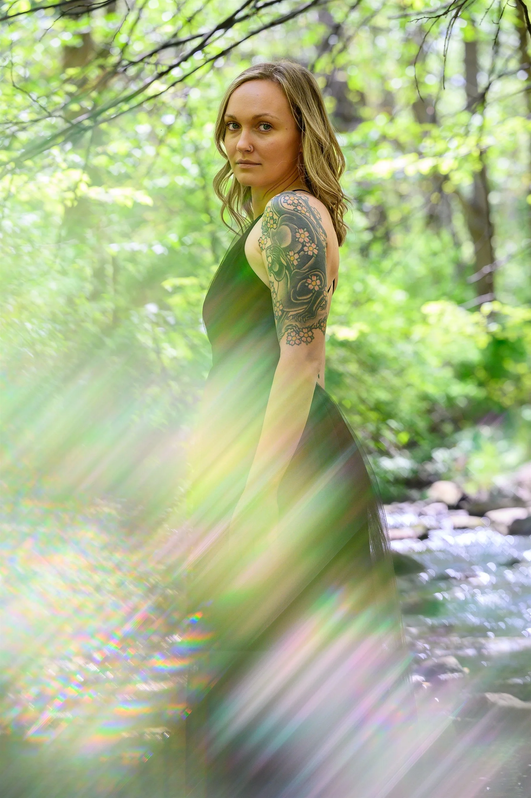 Woman with tattoo in forest, rainbow light effect