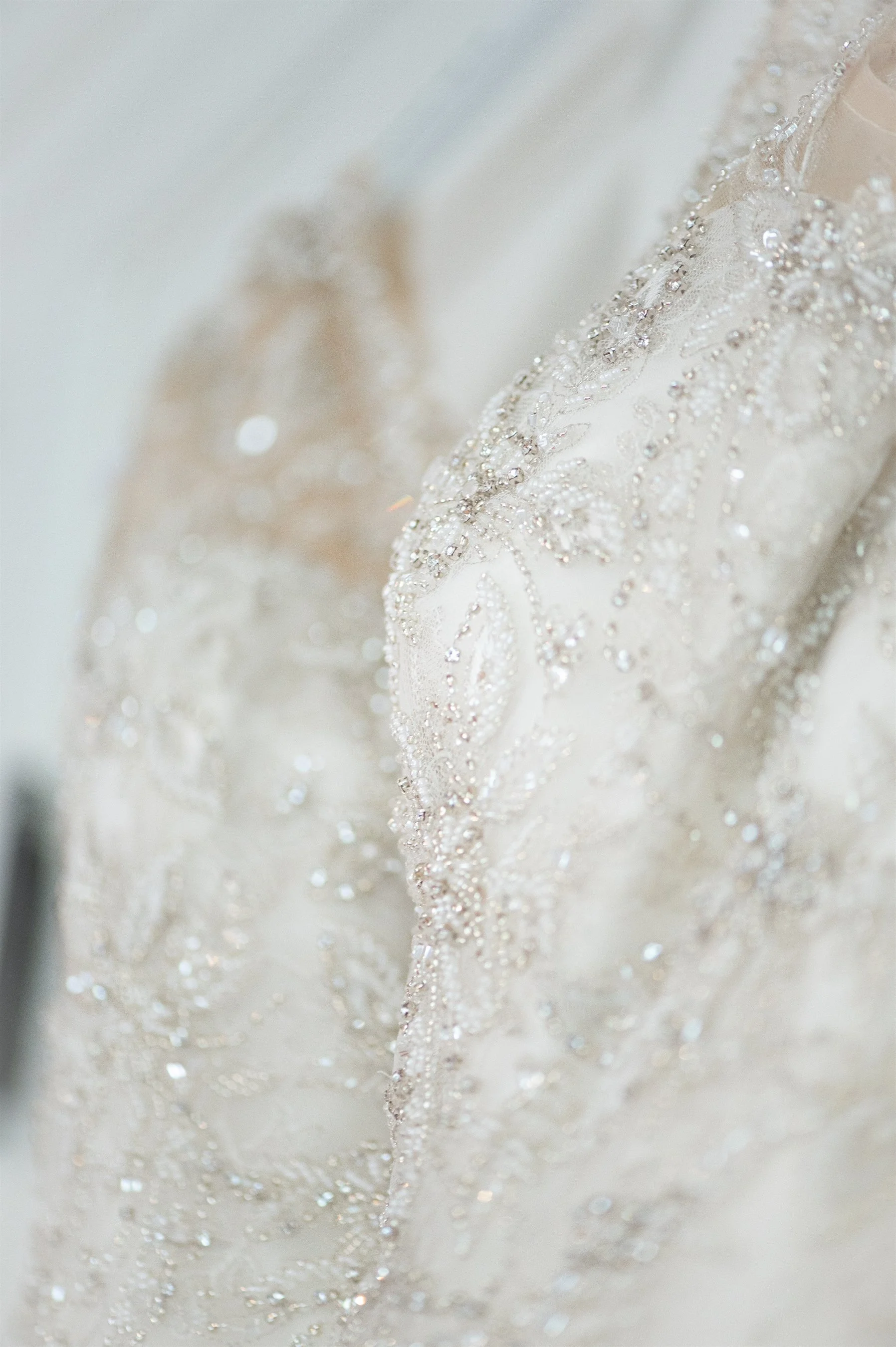 Close-up of a white dress with intricate beaded embroidery and detailed lacework.