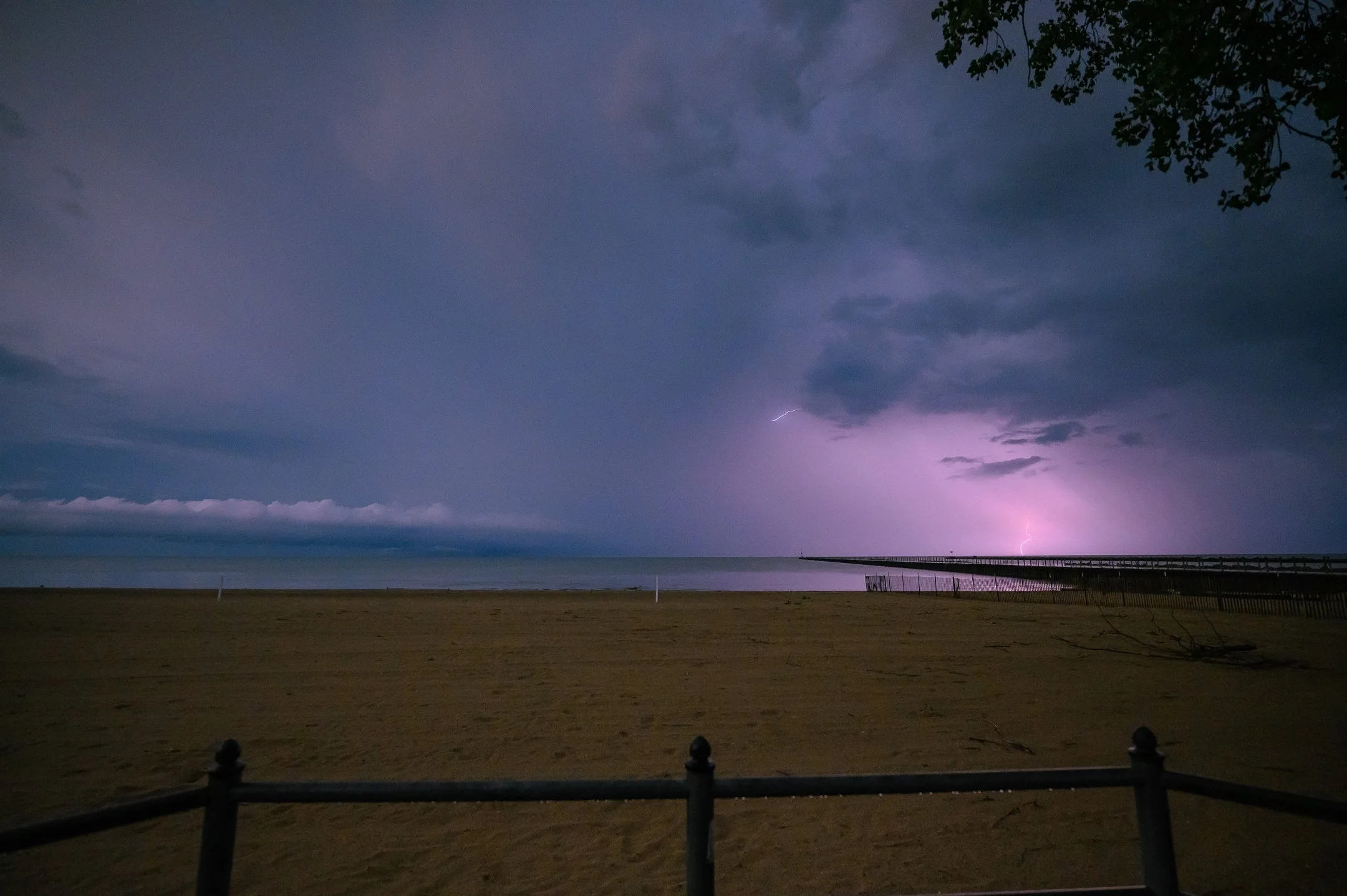 Beach at night with distant lightning over the ocean.