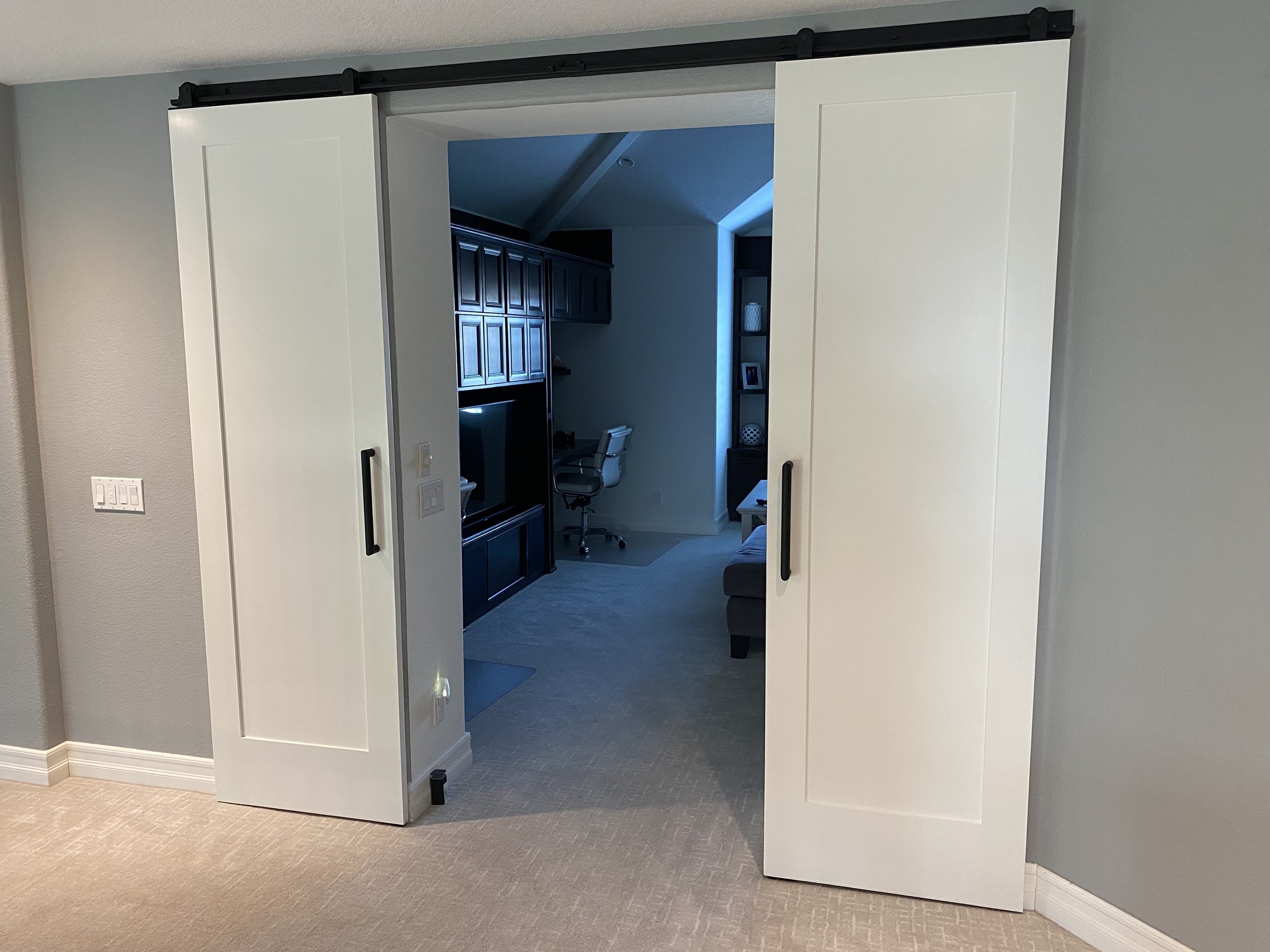 a grey room with white barn doors adorned with modern looking door levers