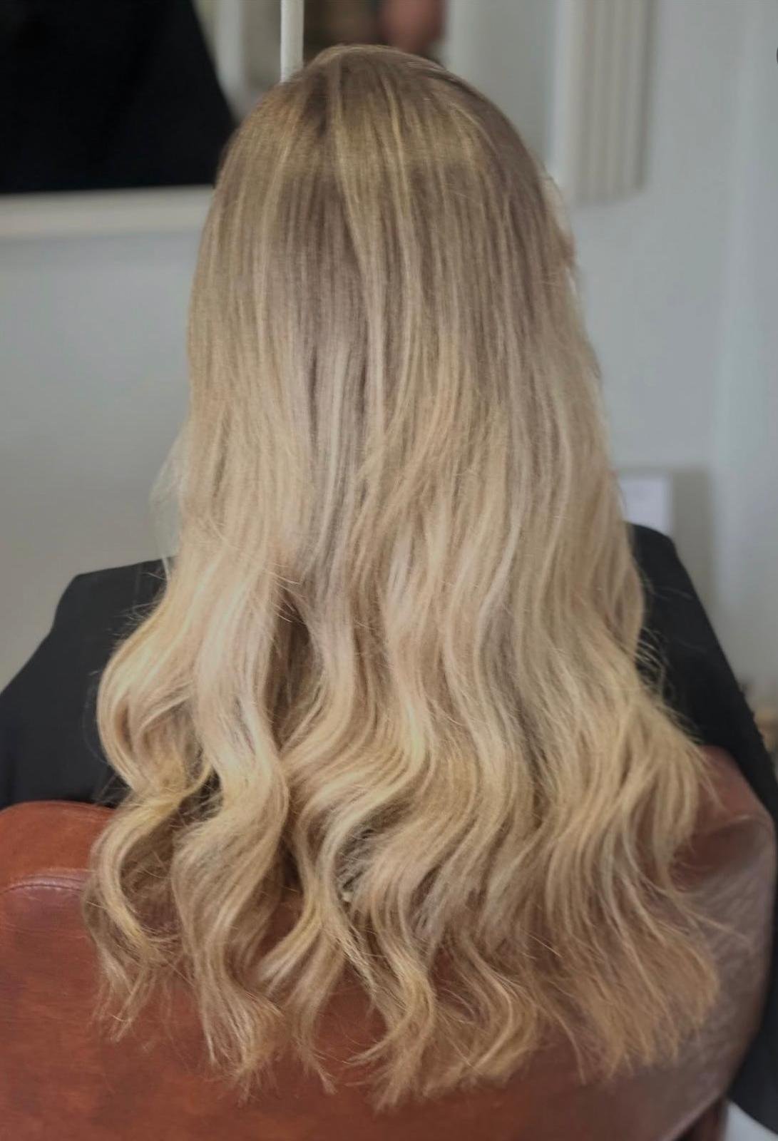 Back of a woman with long, wavy blonde hair.