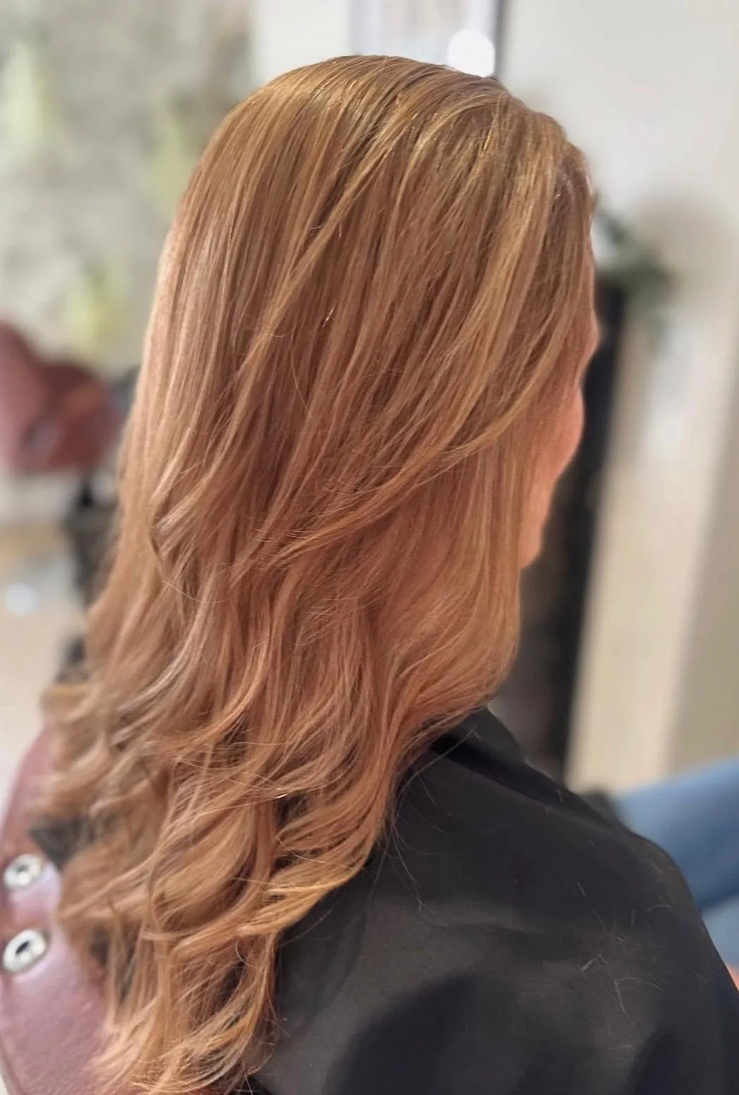 Side view of a woman with long, wavy strawberry blonde hair.