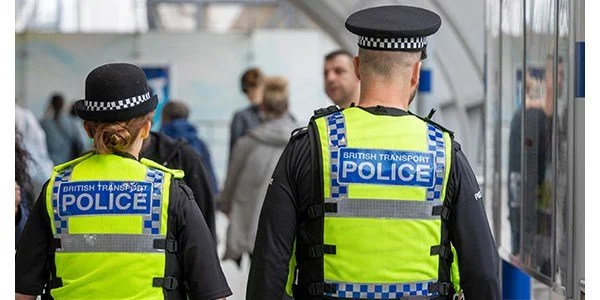 British Transport Police, a man and woman, walking through a station