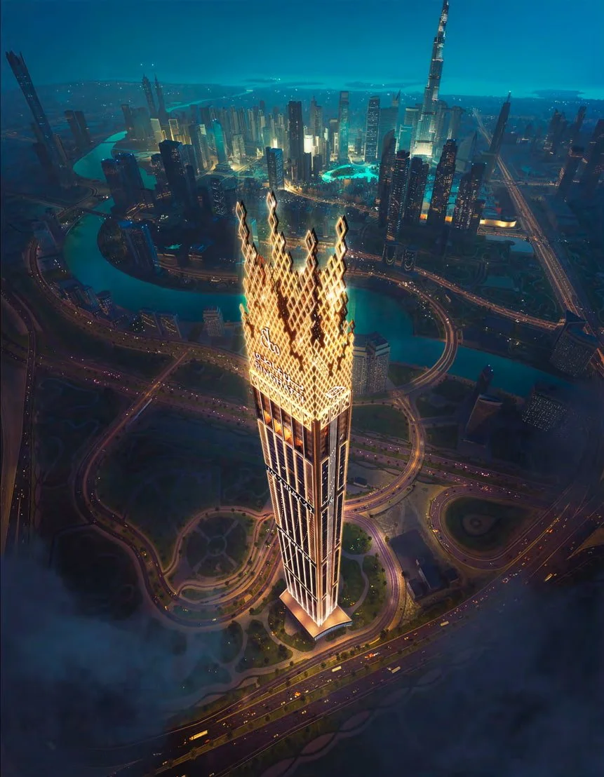 A tall, illuminated skyscraper with a crown-like lit design at the top, set in a modern cityscape at night with surrounding buildings, roads, and waterways.