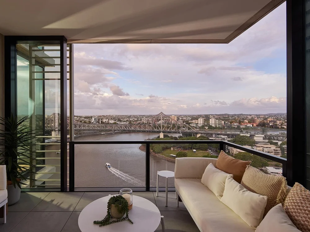 Lounge and verandah with couch and city views in luxury Brisbane apartment at 443 Queen St featured in properties for sale