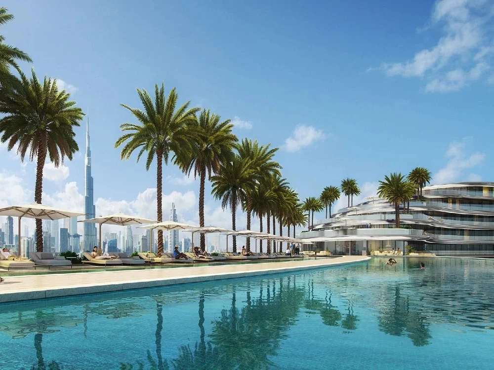 Luxury poolside view at Binghatti Aquarise with futuristic architecture and palm landscaping, showcasing properties for sale in Dubai luxury apartments.