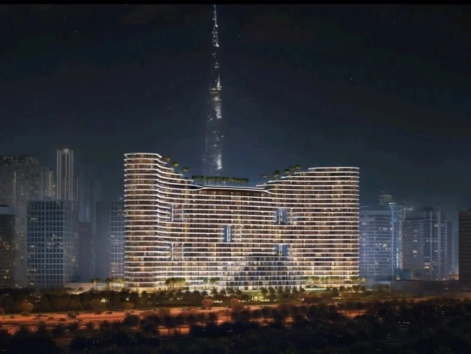 Night skyline of Dubai featuring Binghatti Aquarise tower with Burj Khalifa in backdrop, luxury apartments and properties for sale Dubai.