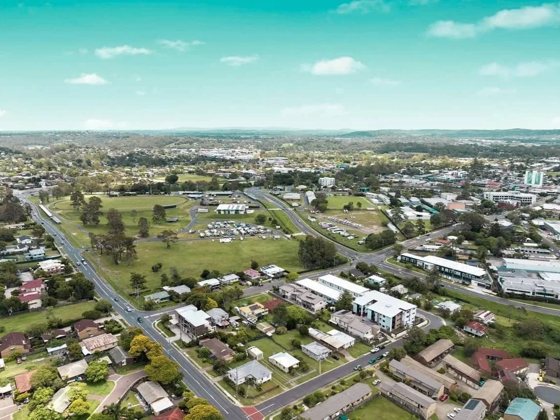 Aerial view of a residential suburb in Beenleigh with homes, parkland and roads, showing the surrounding area of a future development site.