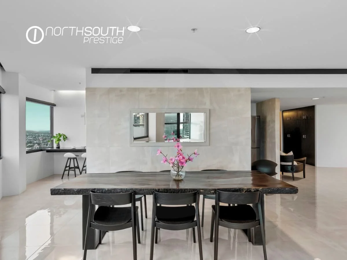 Dining area with a timber dining table, chairs and mirror on the tiled wall - Brisbane properties for sale Riparian Plaza apartment 4903 