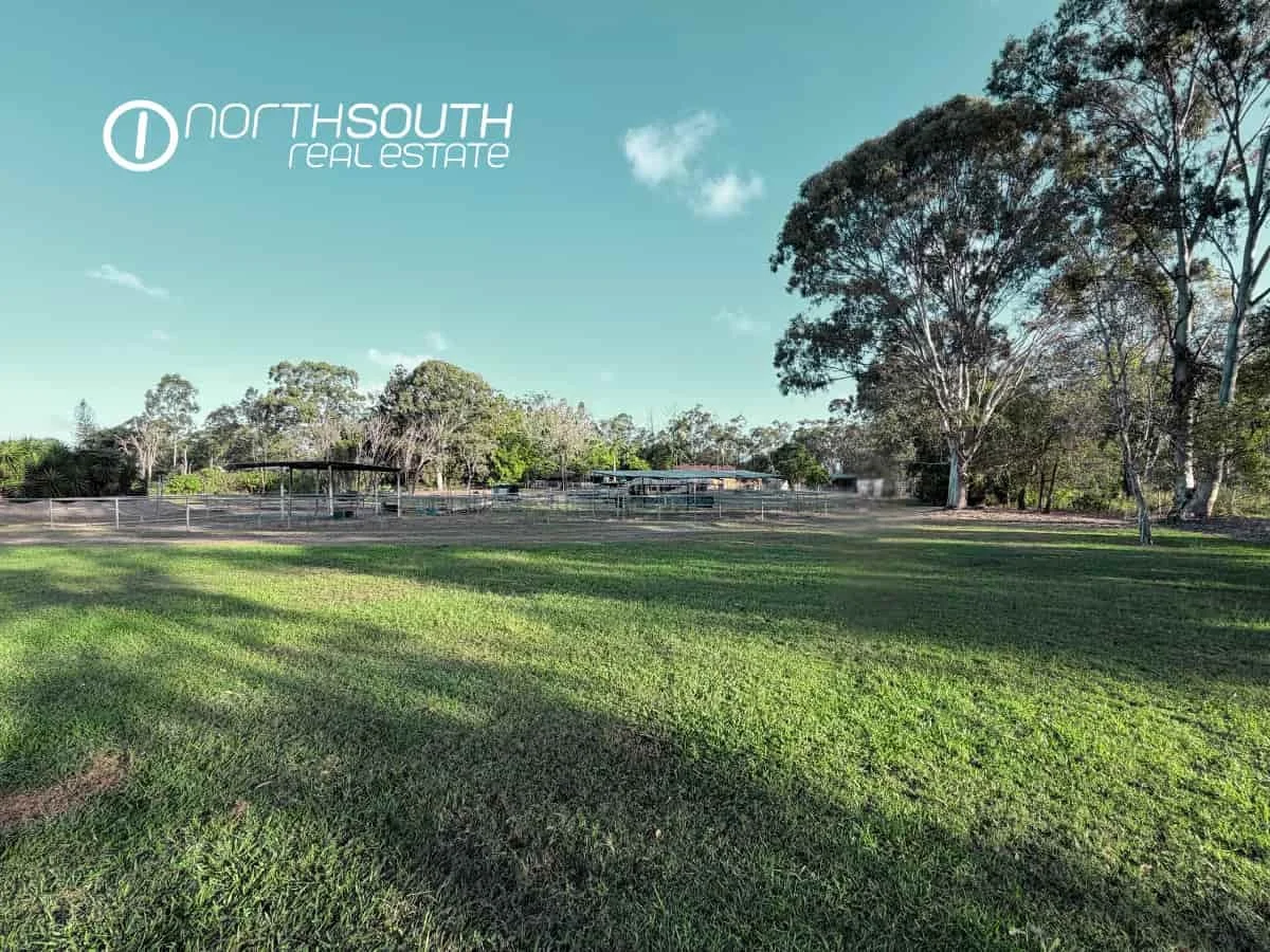 The view of the large parcel of land with trees and stables showcasing lifestyle appeal of a future development site.