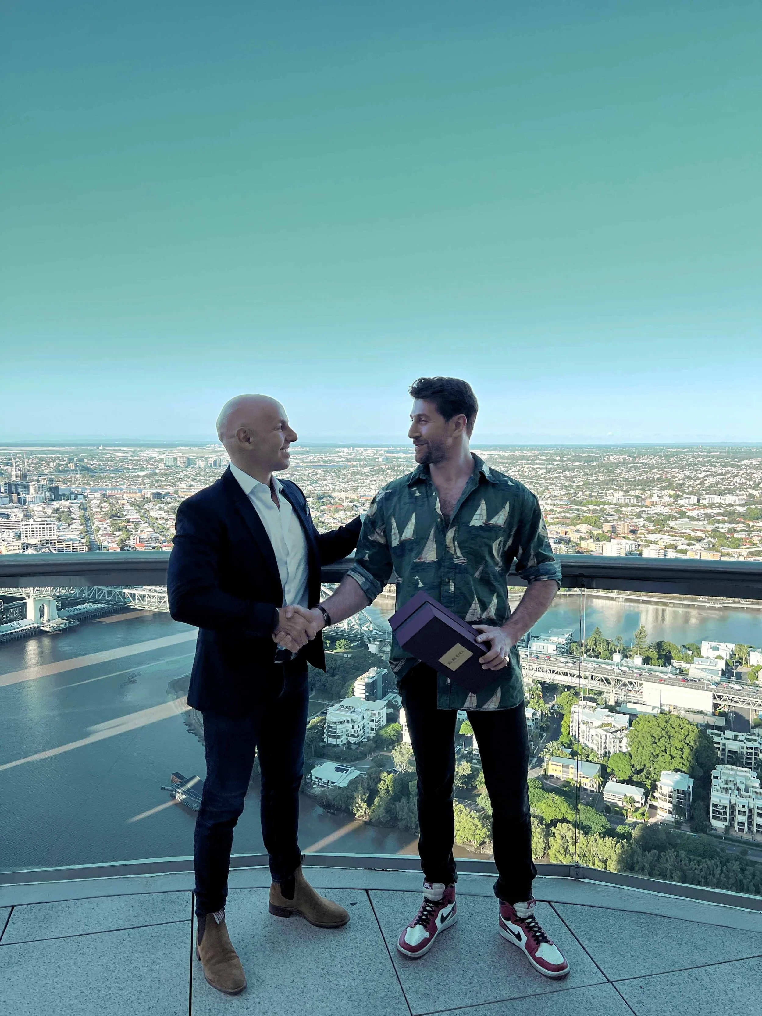 High-net-worth client congratulated by luxury real estate agent Nik Seirlis of NSRE director after high-end real estate purchase on Brisbane River