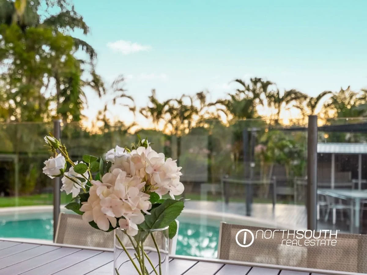 View of the pool at sunset from the outdoor table with a flowers in a vase at 7 Bligh Street, Rochedale South QLD 4123