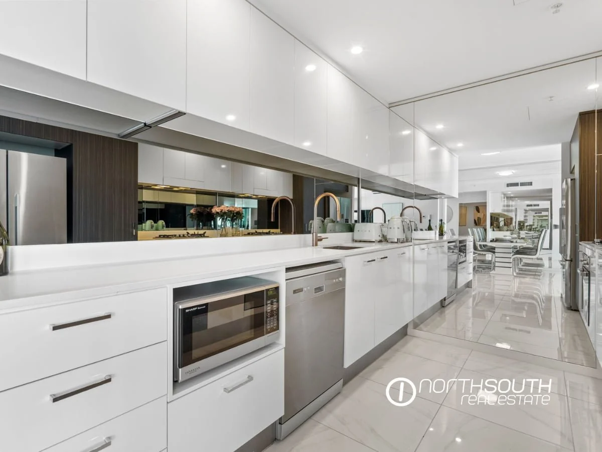 Kitchen with mirrored splashback,  pantry and large cupboards at  3303/5 Harbourside Ct Waterpoint Residences, Biggera Waters QLD.